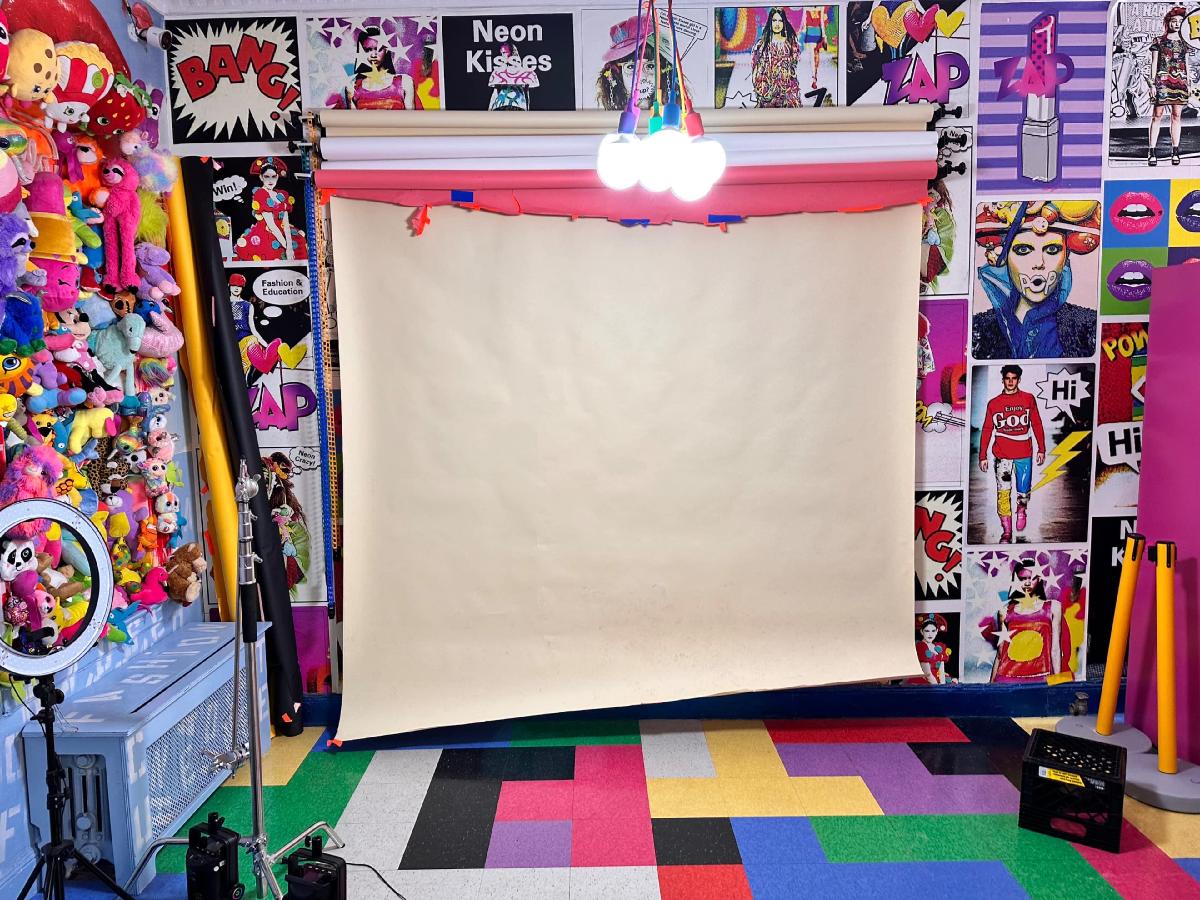 A colorful studio set with a plain backdrop, surrounded by vibrant decor and a variety of plush toys.