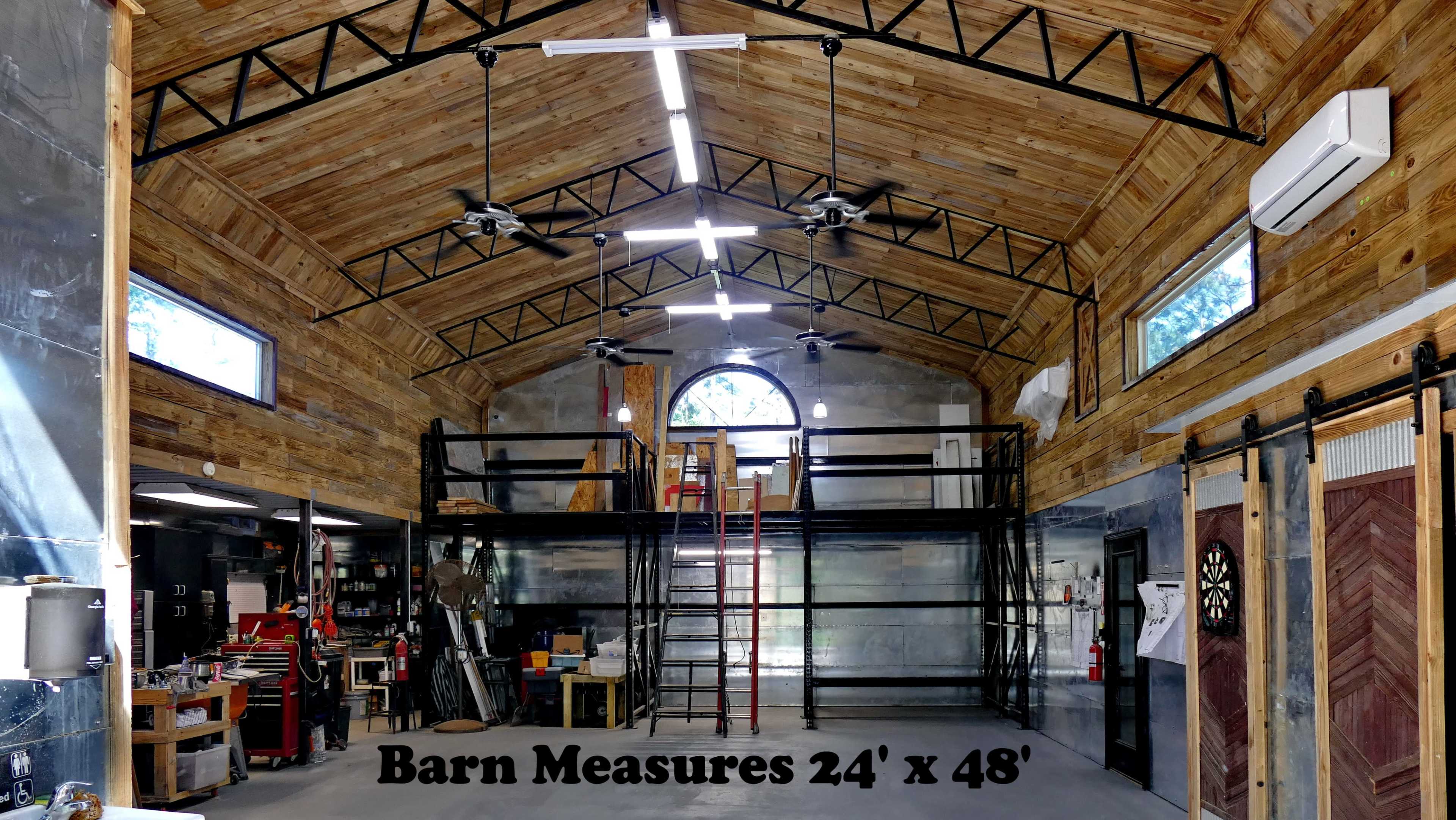 The interior of a spacious barn measuring 24 feet by 48 feet, featuring wooden walls, a loft area, and various tools and equipment arranged within.