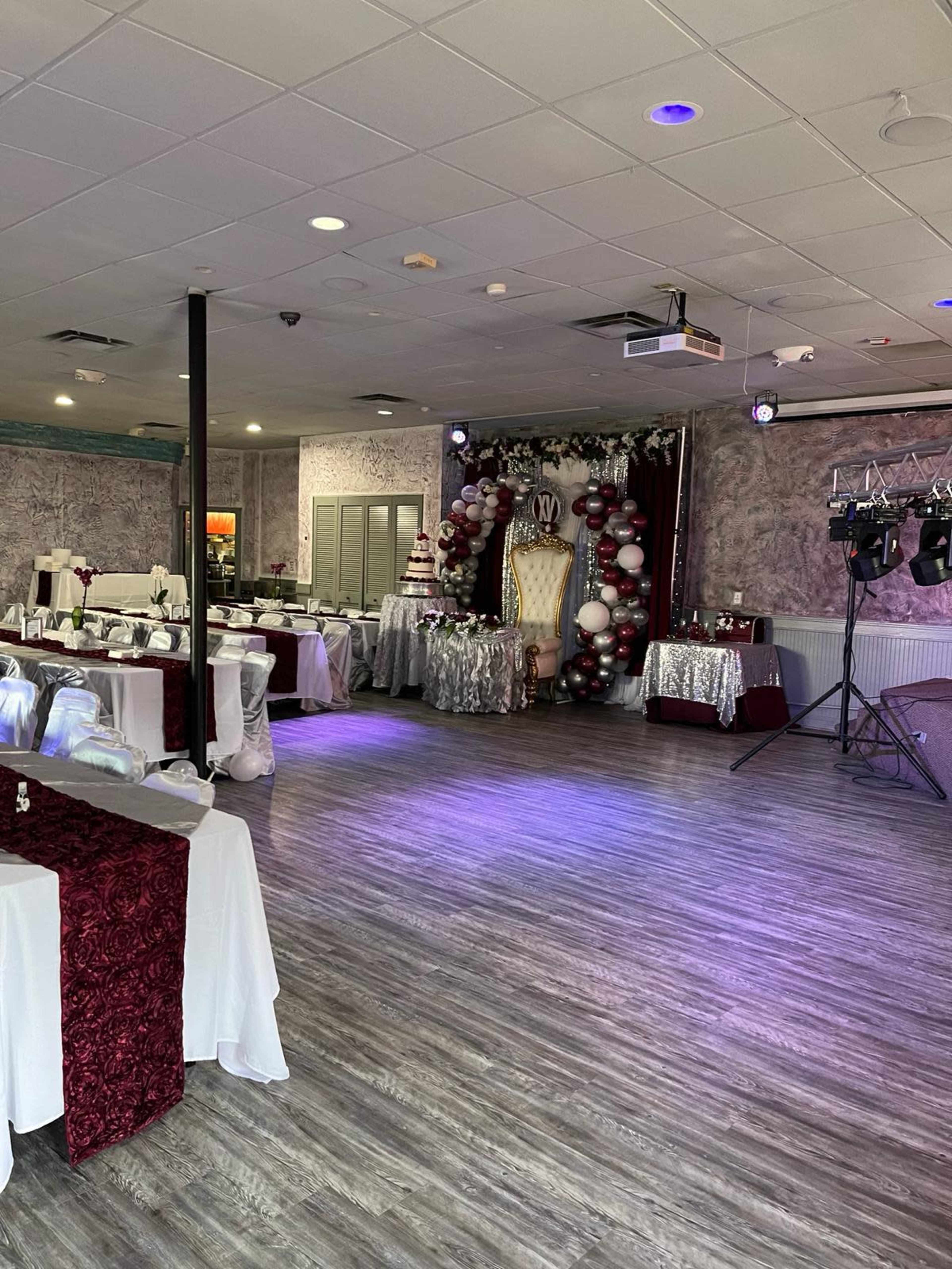 A decorated event space with tables set up and a backdrop featuring balloons and a cake display.