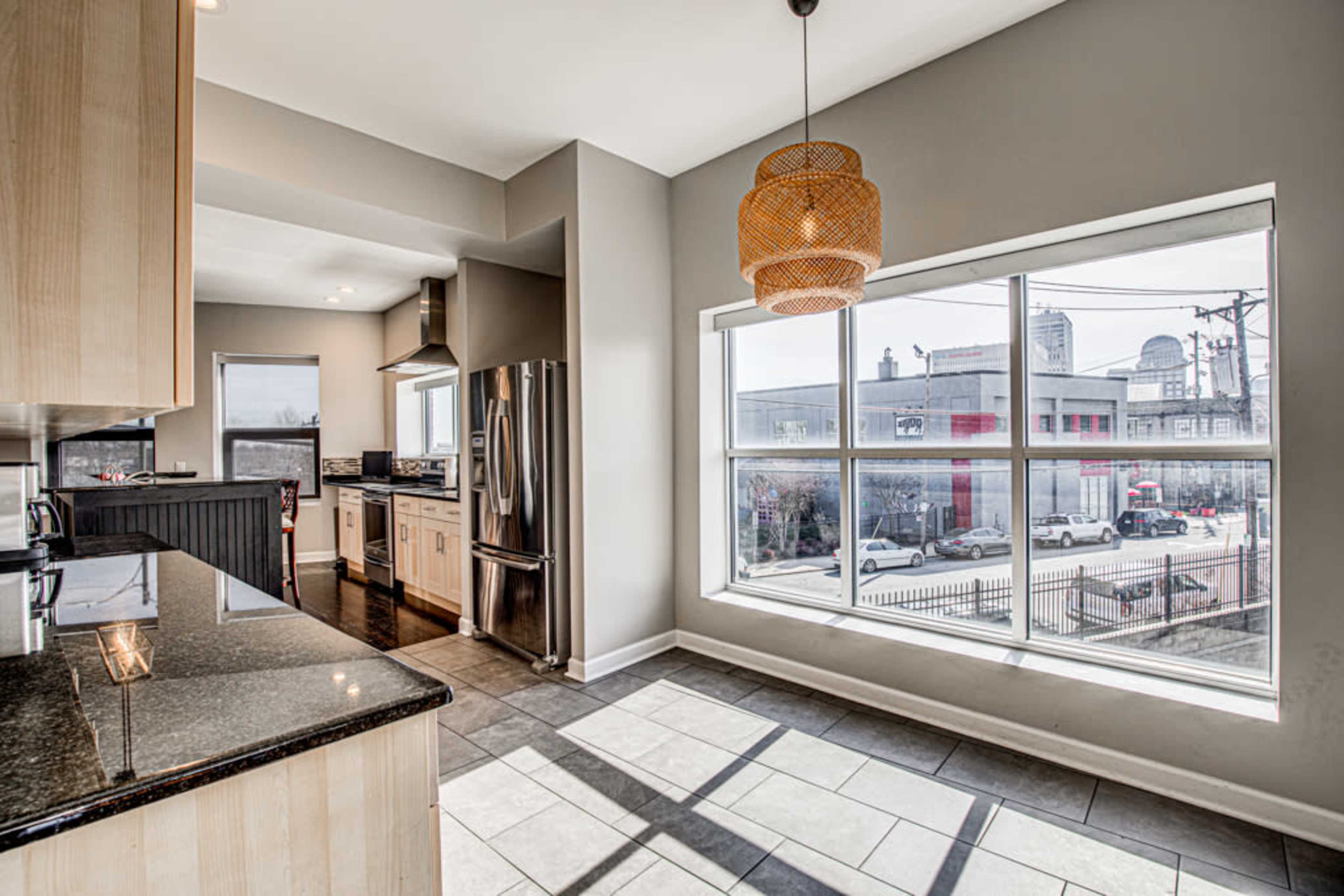 A modern kitchen with gray walls, a large window, and stainless steel appliances.