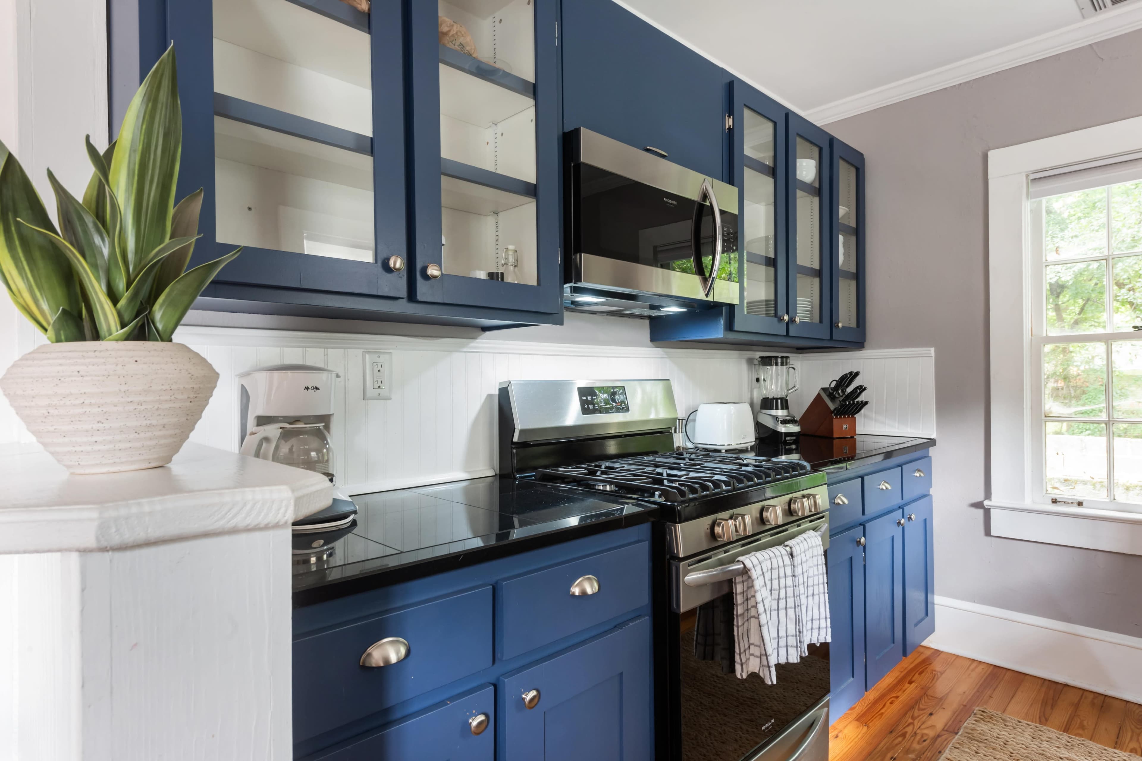 The kitchen features blue cabinetry with glass-paneled doors, stainless steel appliances, and a black countertop.