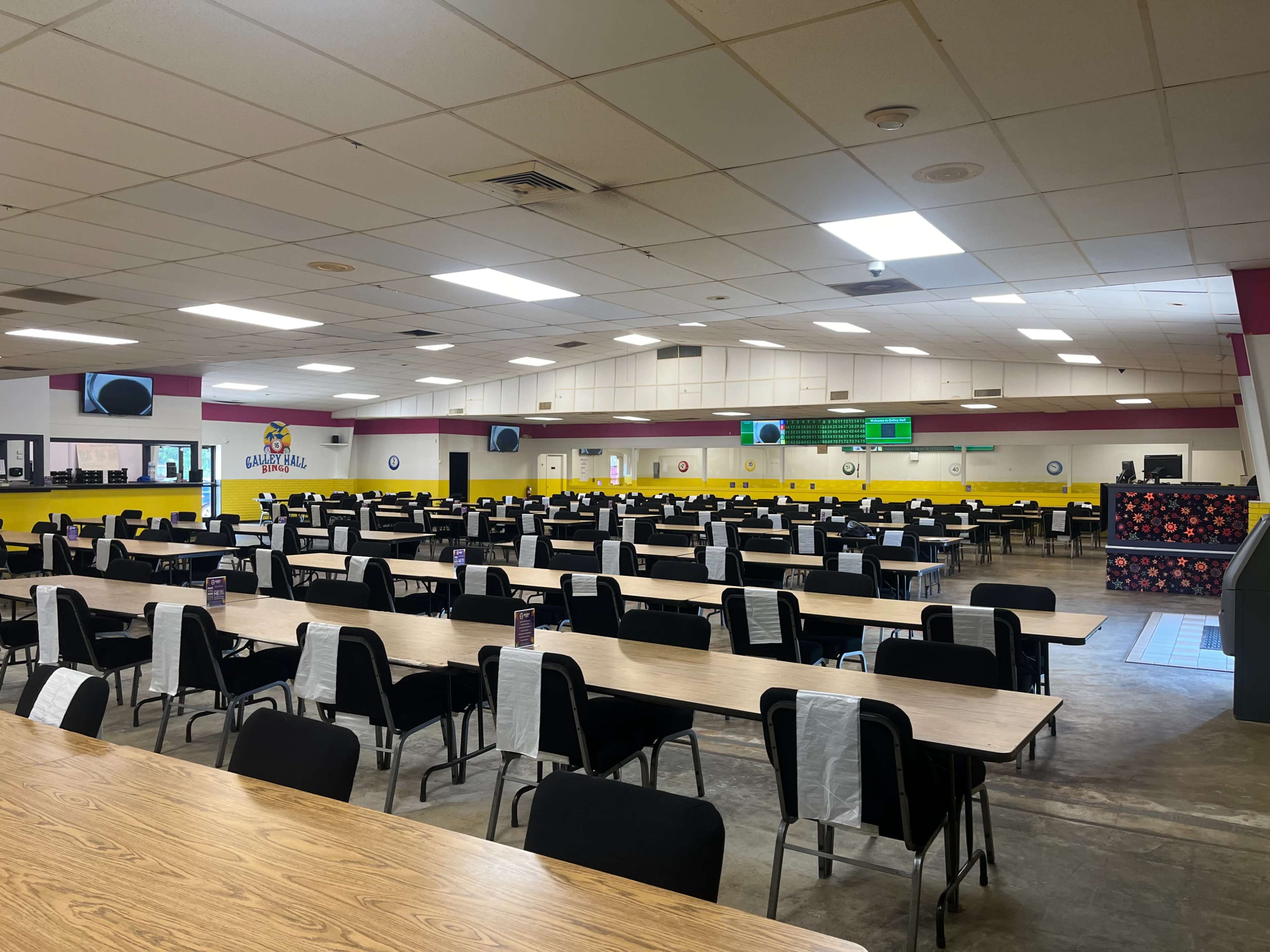 A large, empty cafeteria with many rows of tables and chairs arranged throughout the space.