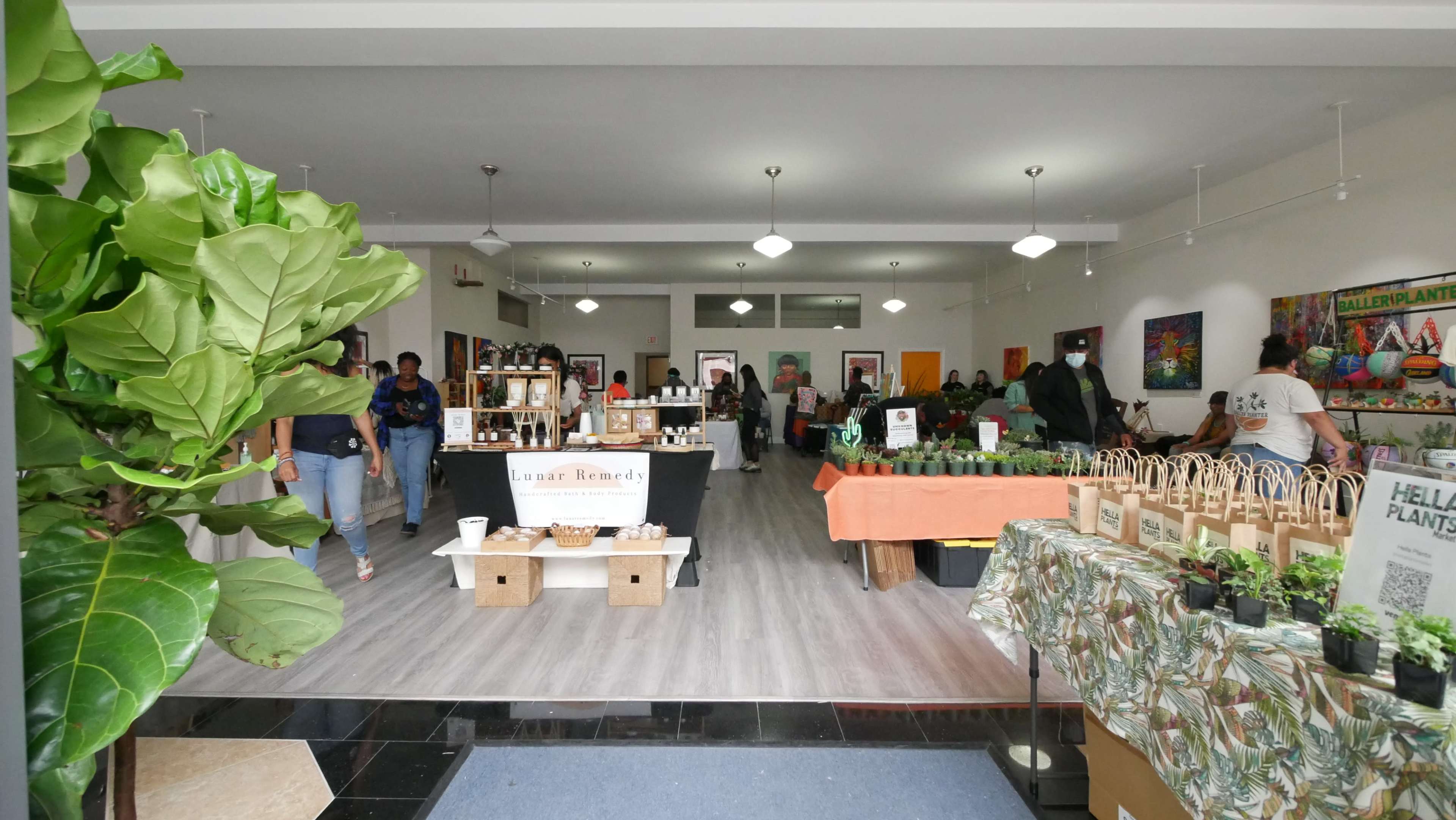A busy indoor market filled with tables displaying plants and various products, while people browse and shop.
