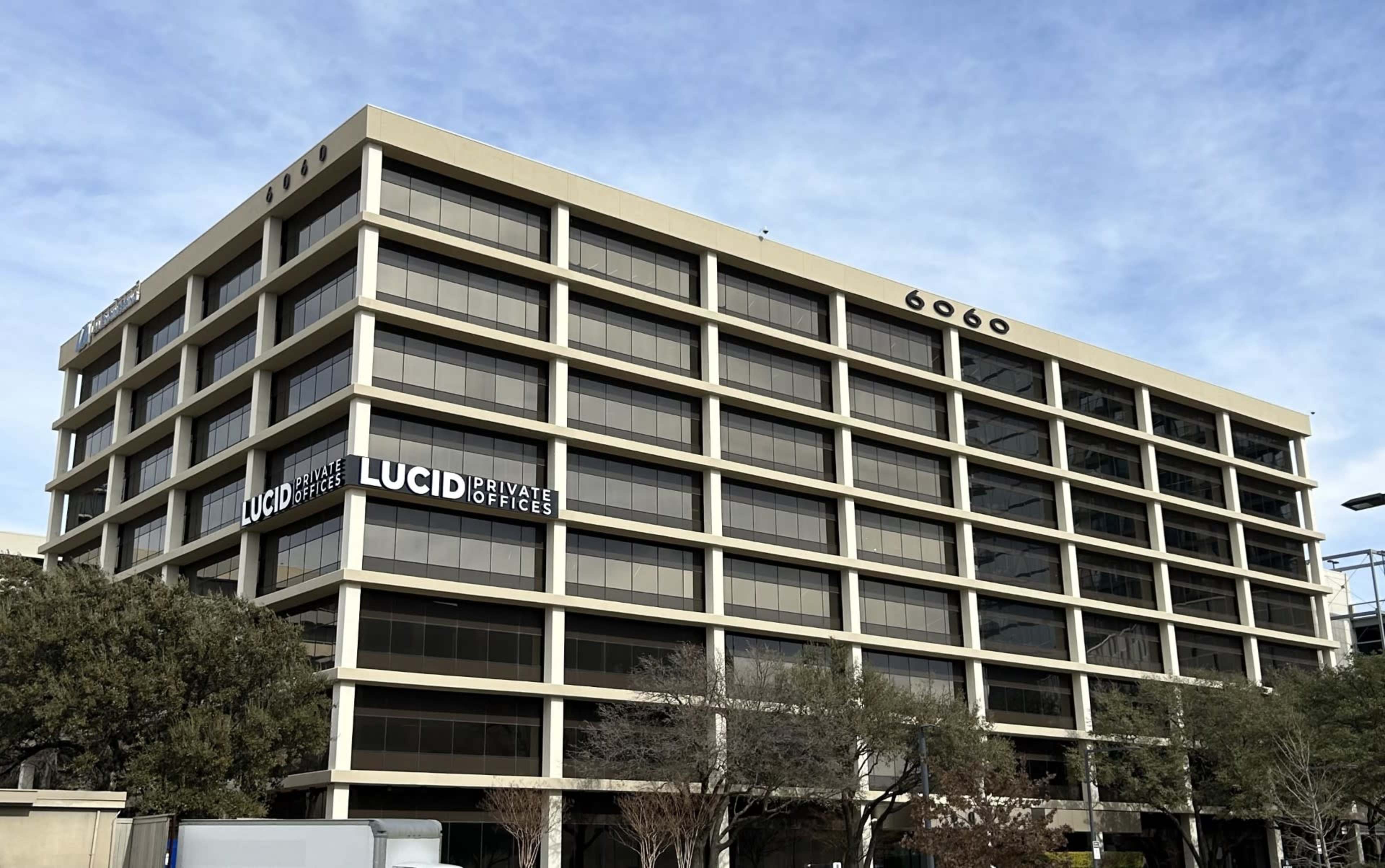 The image shows a five-story office building with large windows and a sign for "Lucid Private Offices" on the side.