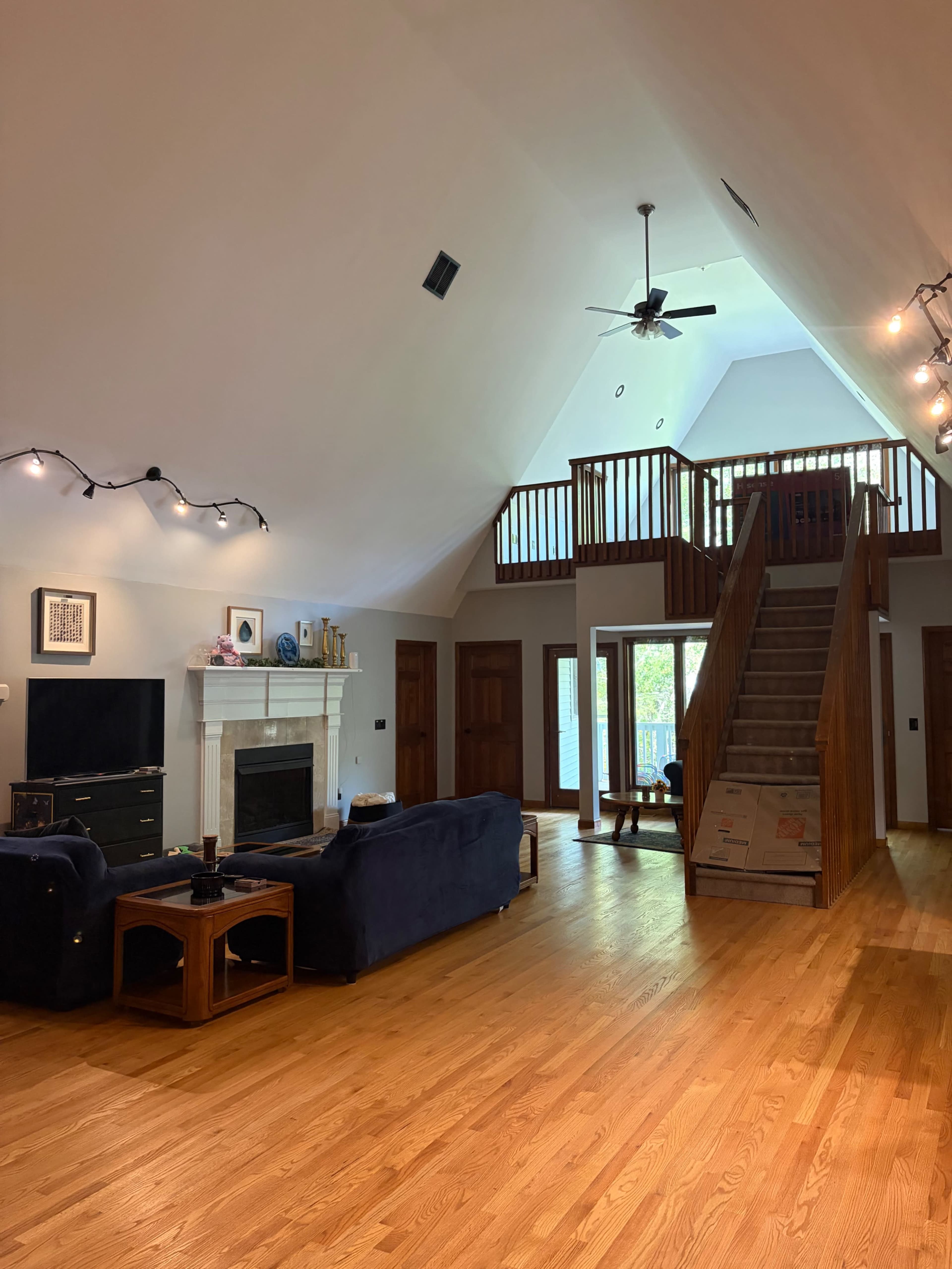 A spacious living room features a fireplace, a large window, and a staircase leading to a second level.