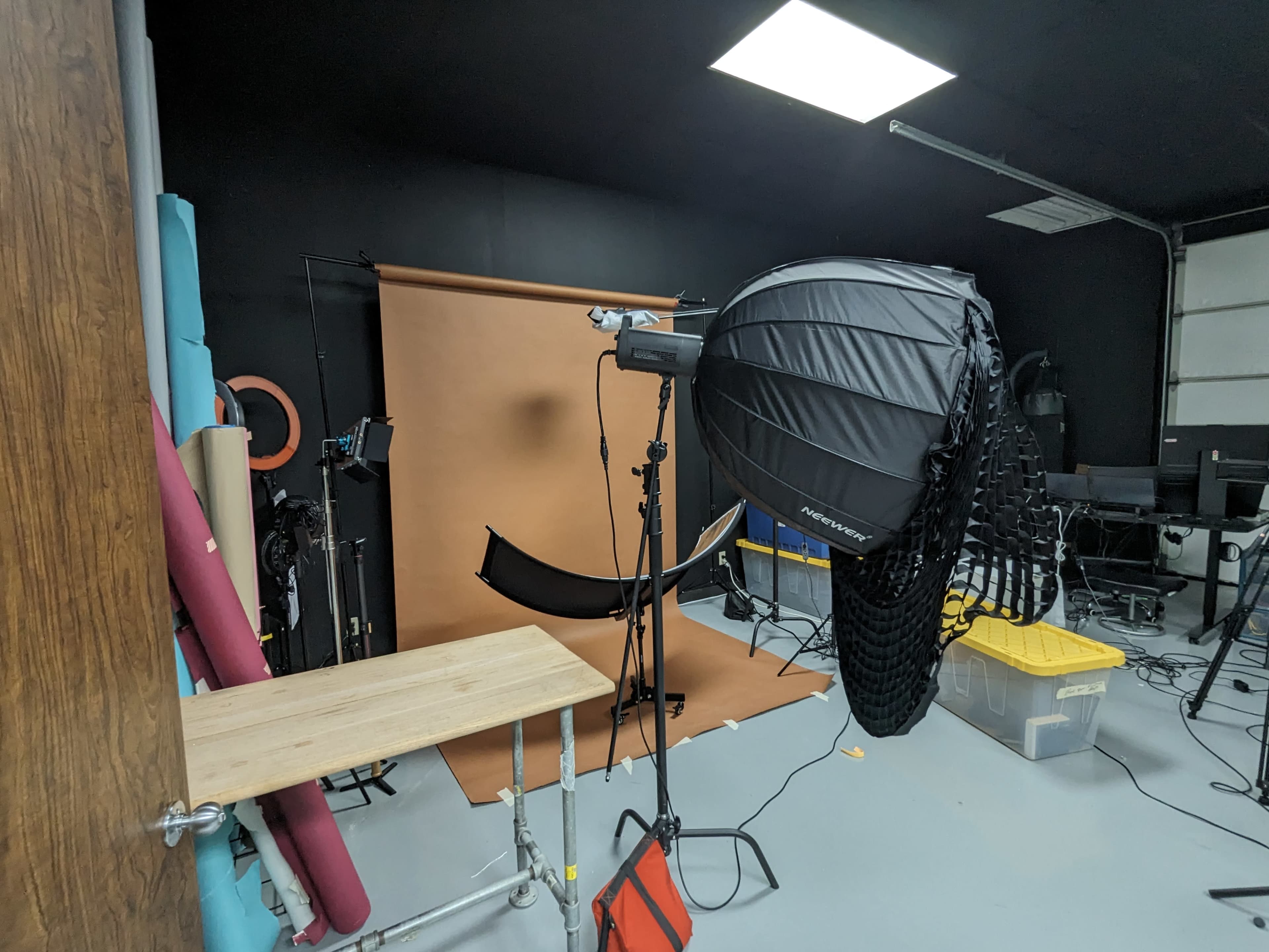 A photography studio setup with a large umbrella light, a backdrop, and various equipment arranged in the space.