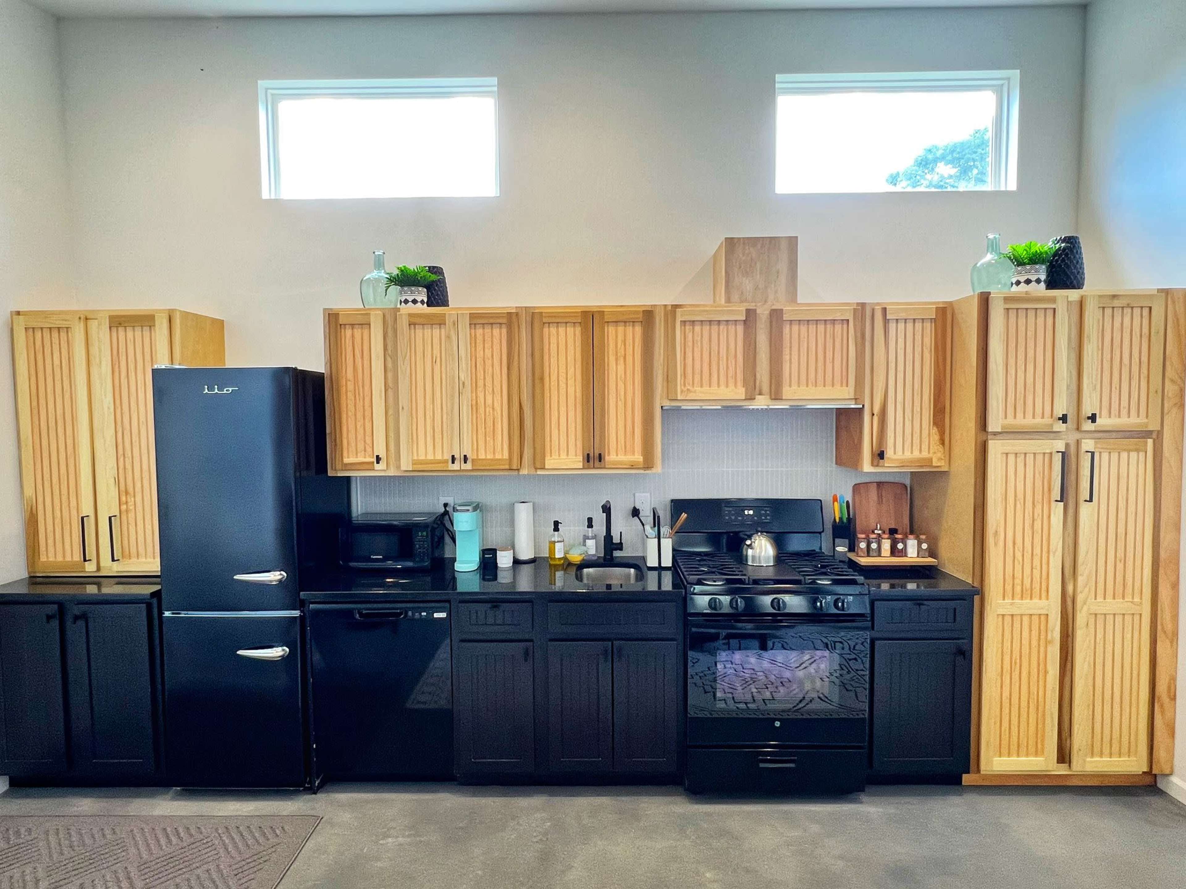 A modern kitchen with black appliances and wooden cabinetry, featuring a gas stove and a countertop.
