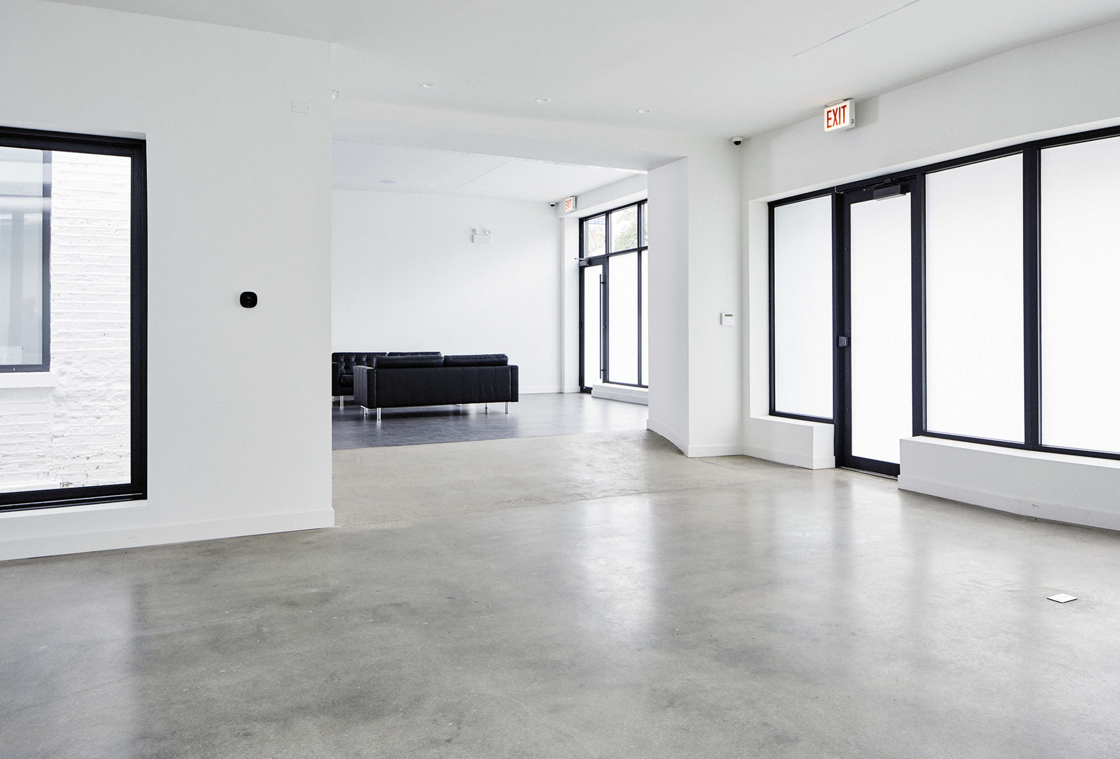 A spacious, minimalist interior with concrete flooring and large windows.