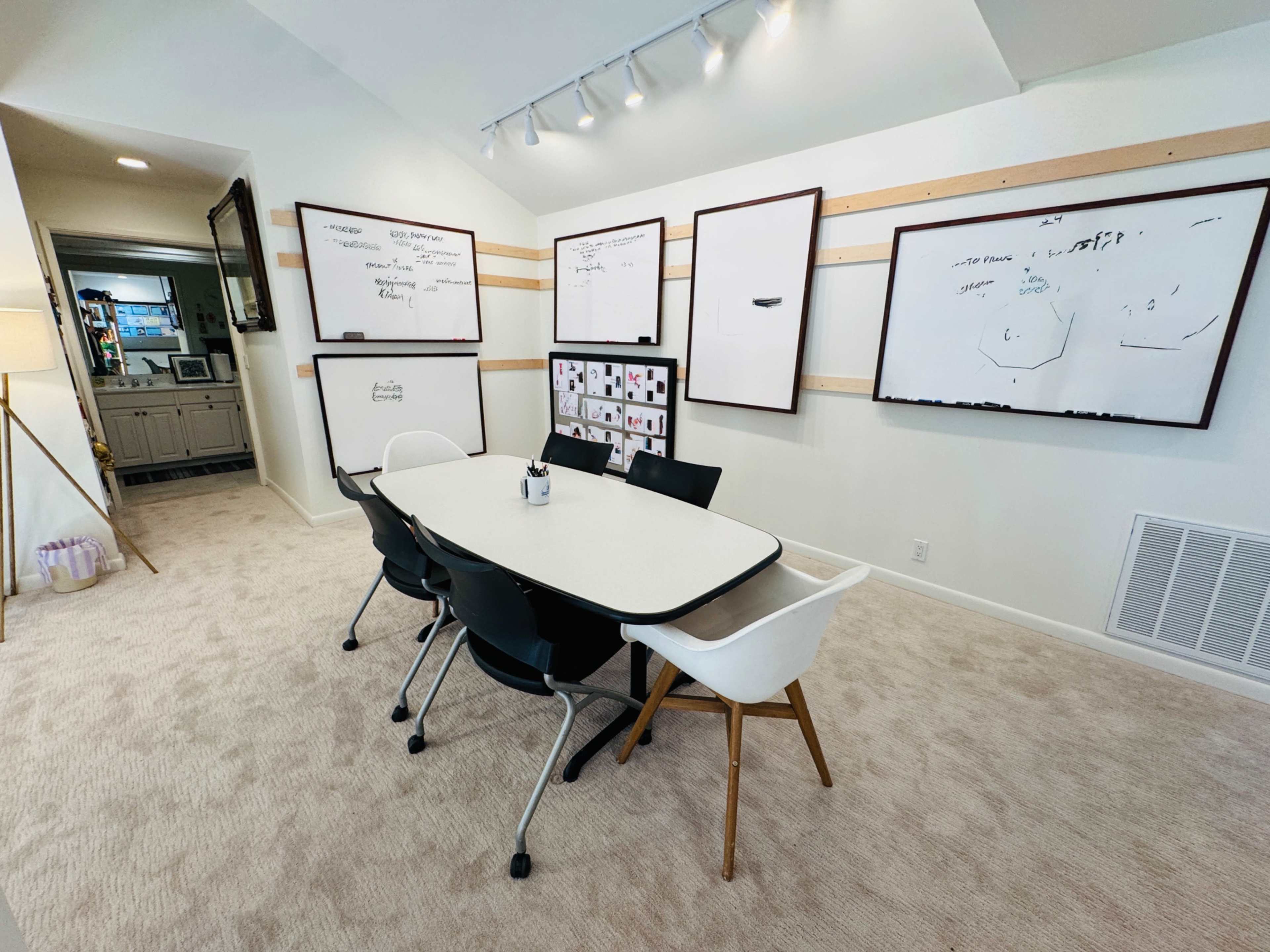 A modern meeting room features a large oval table surrounded by black and white chairs, with whiteboards on the walls for brainstorming.