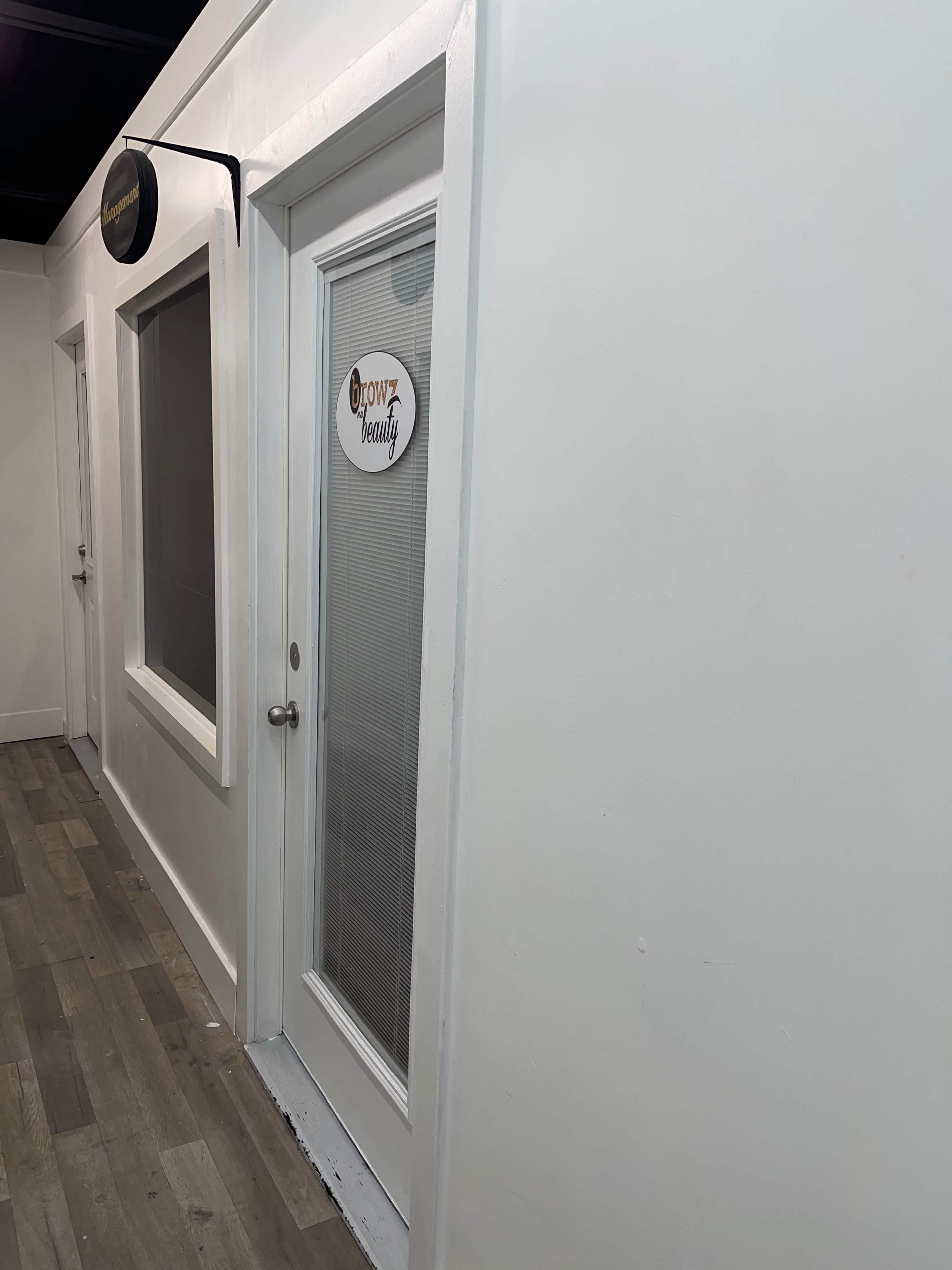 A narrow hallway with a door labeled "Grow Your Beauty" and adjacent windows on a white wall.