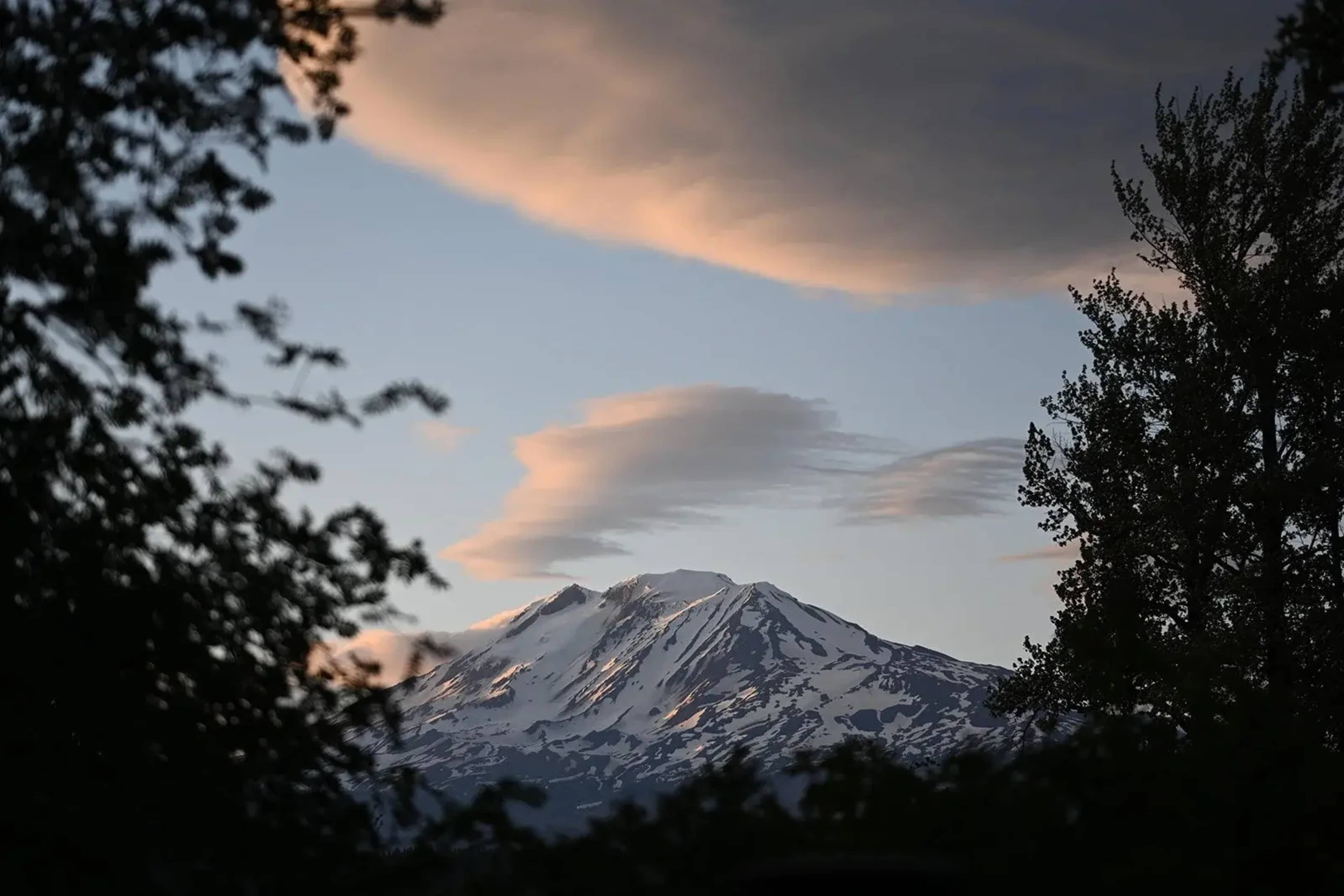 A snow-capped mountain rises against a twilight sky with wispy clouds.