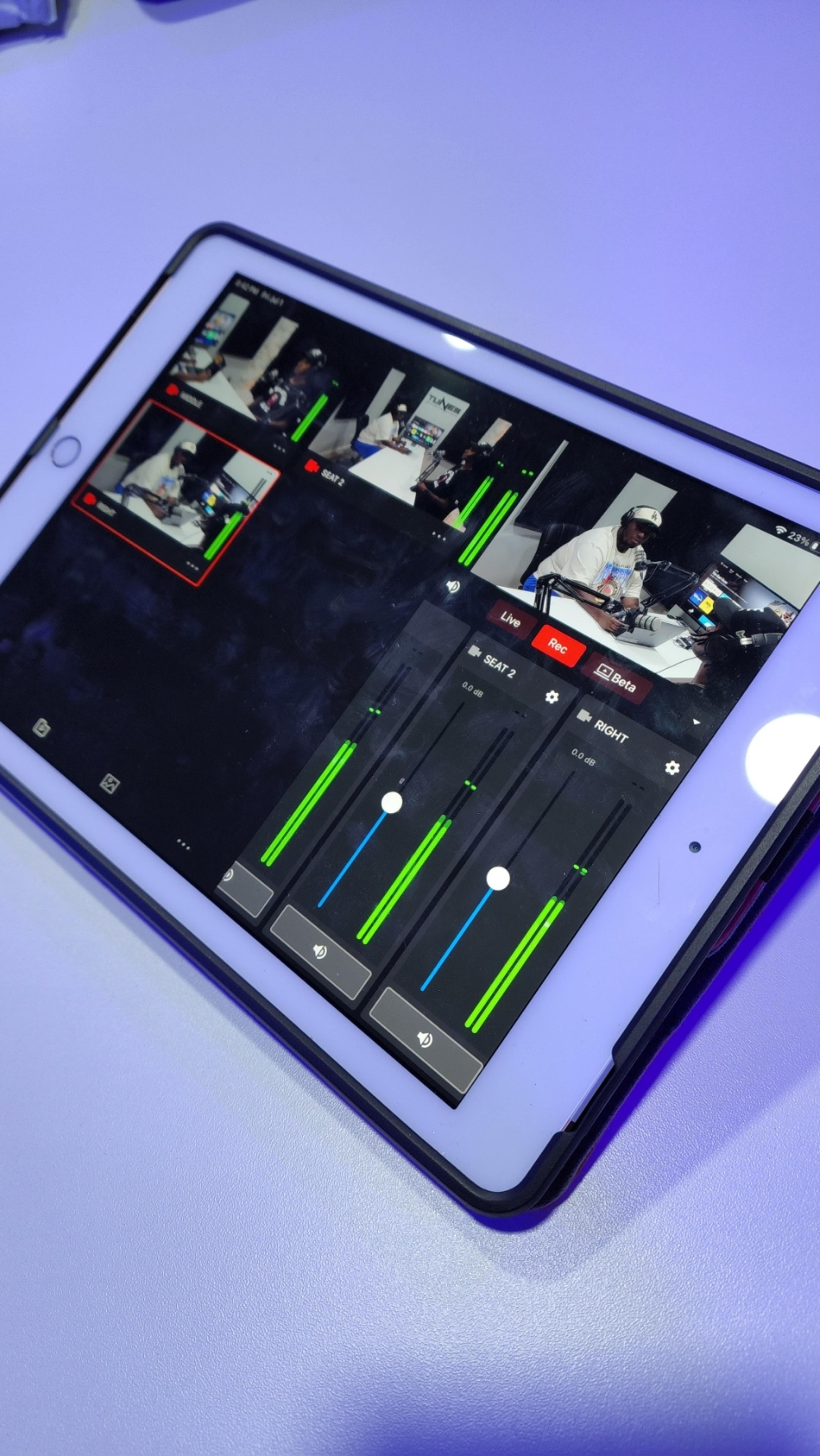 A tablet displays a video mixing interface with multiple camera feeds and audio level controls.
