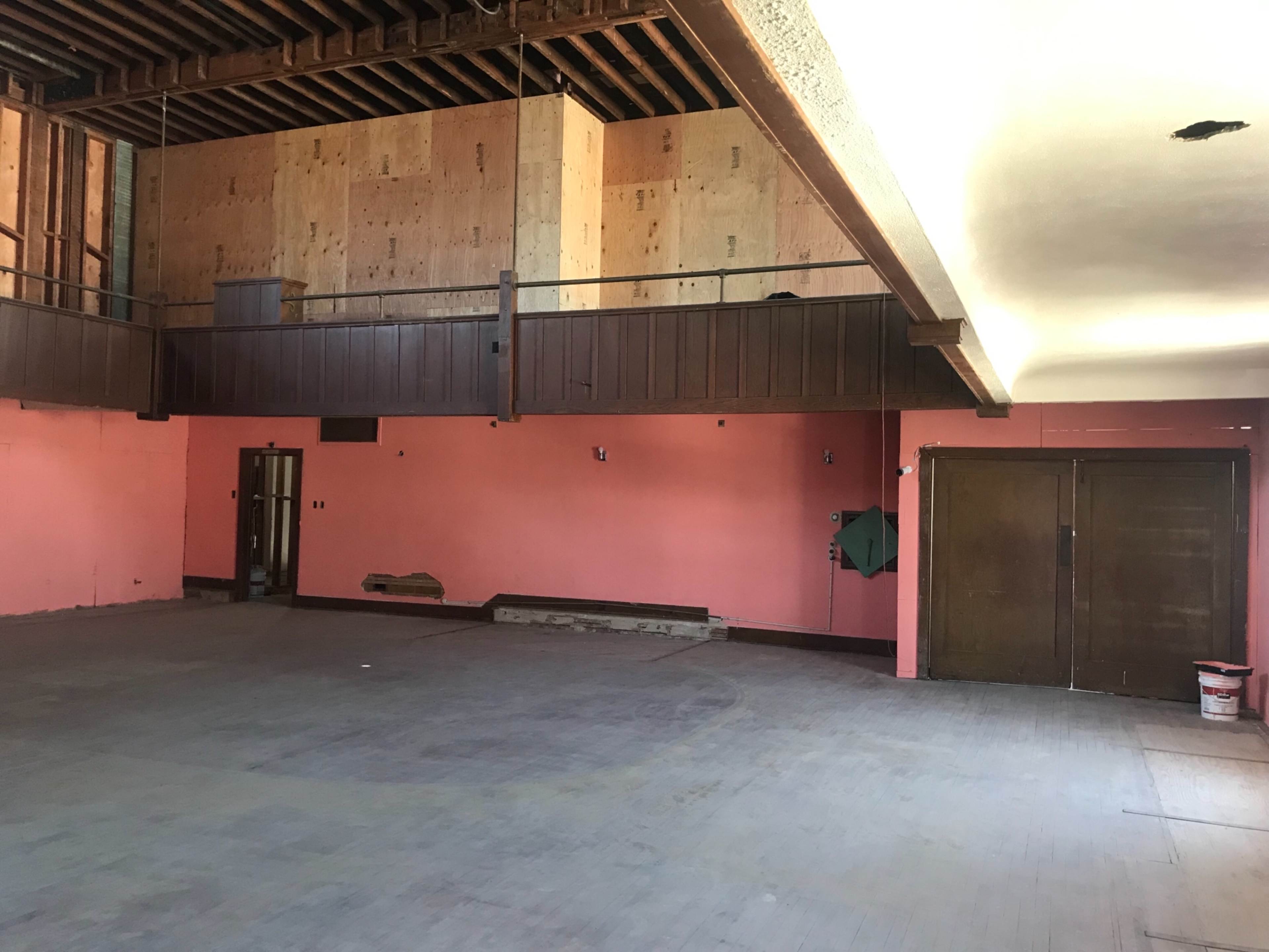 An unfinished interior space with pink walls, wooden beams, and bare flooring.