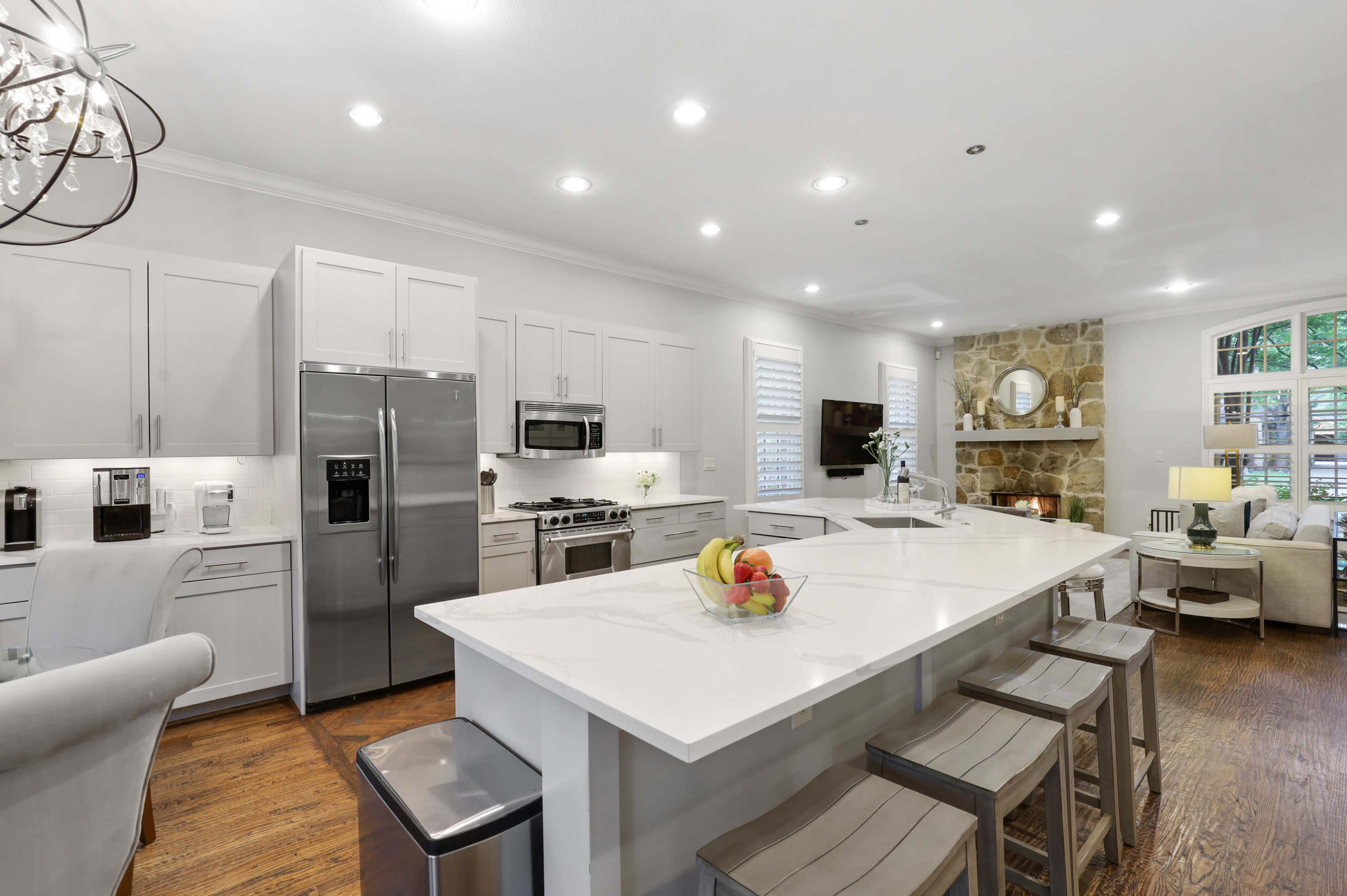 A modern kitchen with a large island, stainless steel appliances, and a cozy seating area with a stone accent wall.