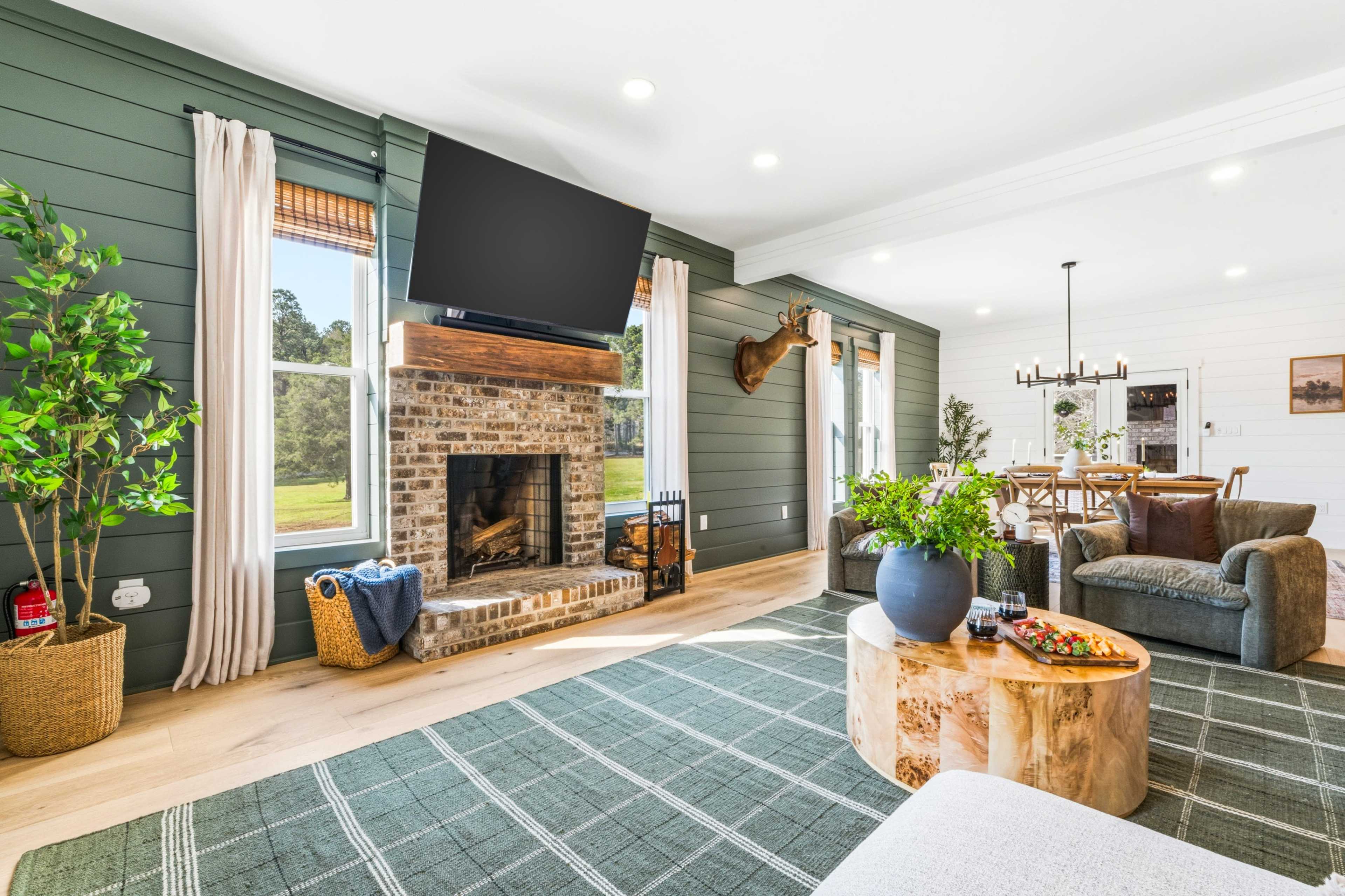 The living room features a brick fireplace, large windows, and a mix of modern and rustic decor elements.