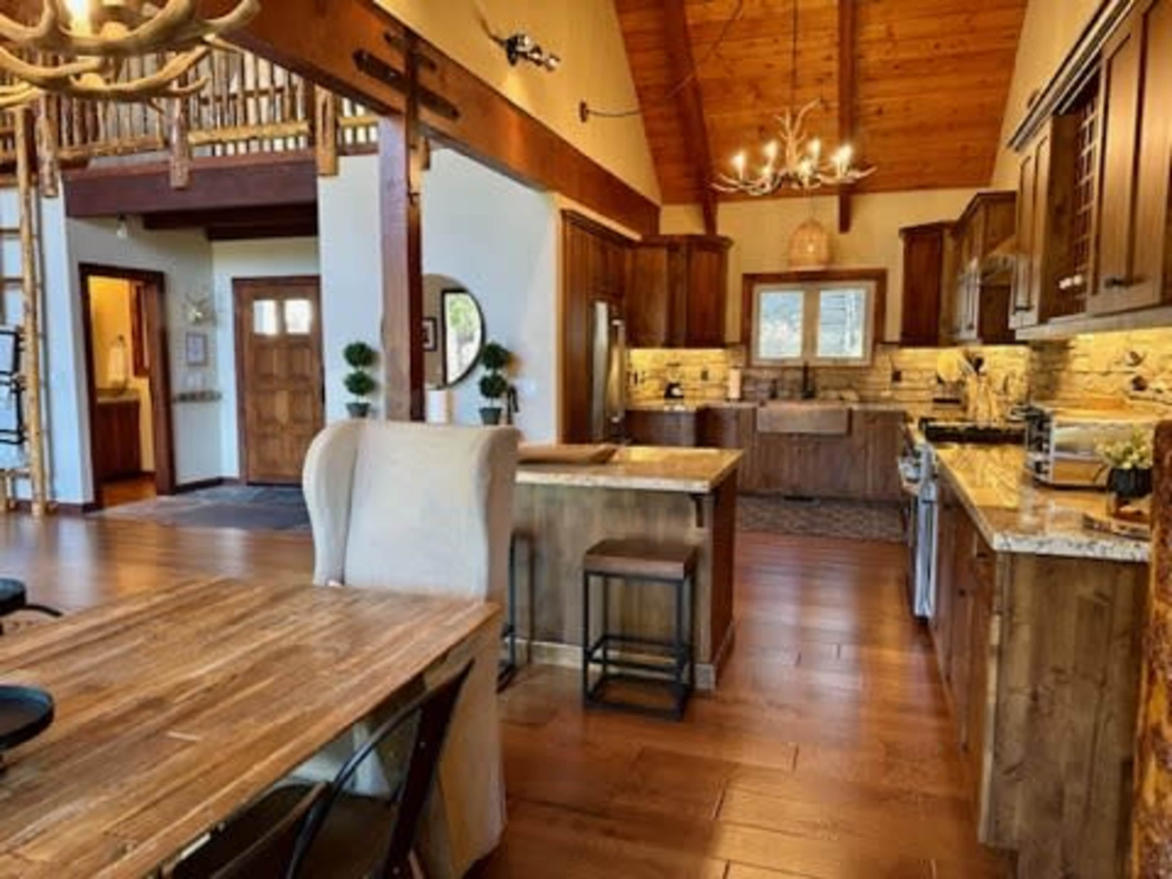 An open-concept kitchen and dining area with wooden beams, modern appliances, and a large central island.