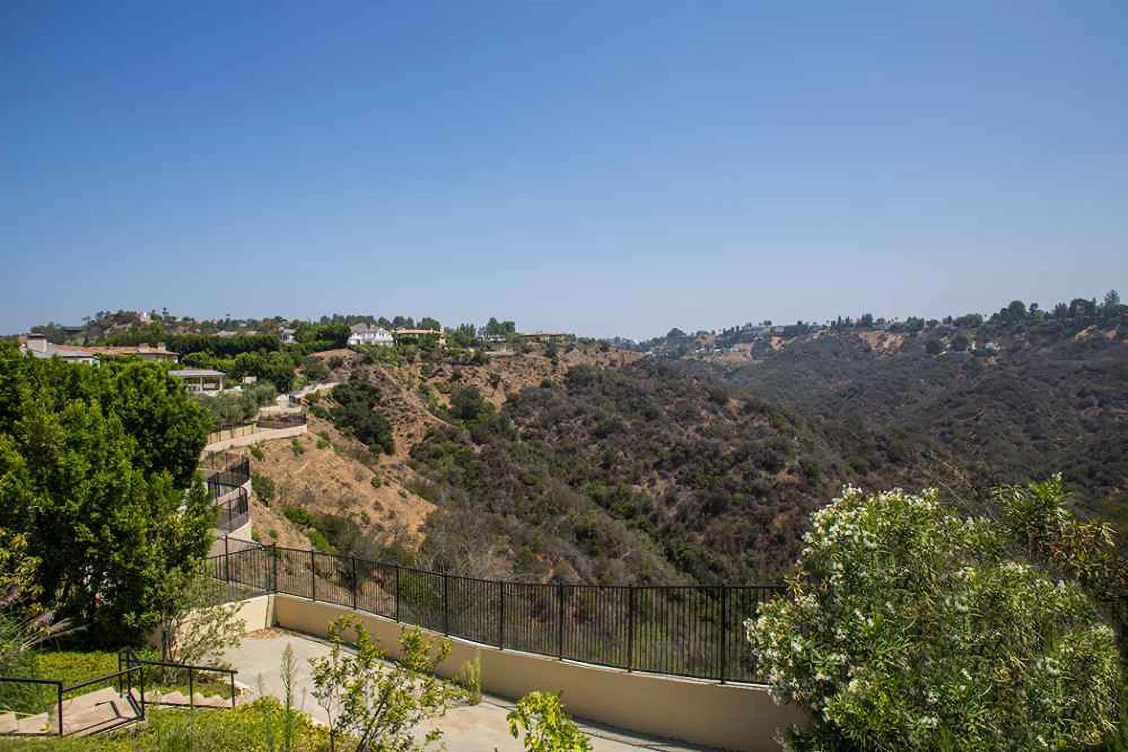 A landscape featuring a steep canyon with houses on the hillside under a clear blue sky.