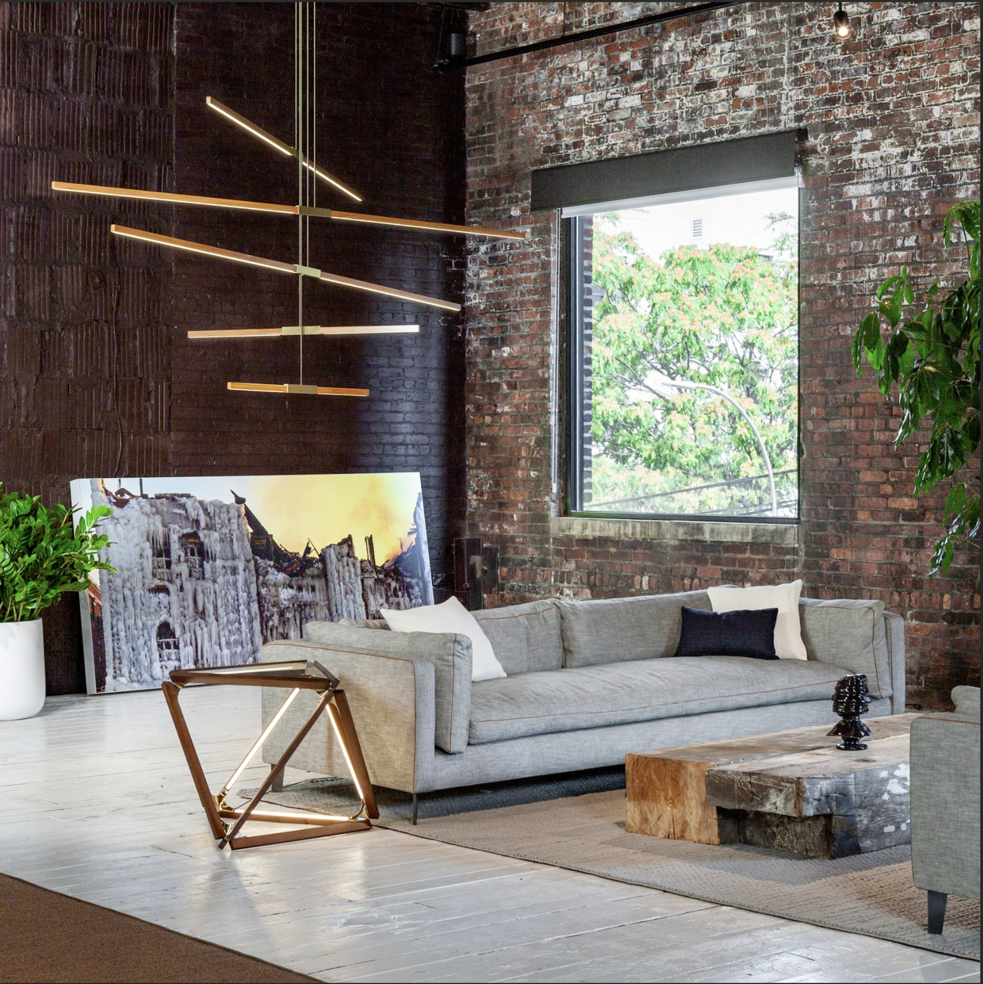 The image shows a modern living room with a gray sofa, a coffee table made of stone, and large windows that allow natural light to illuminate the space.