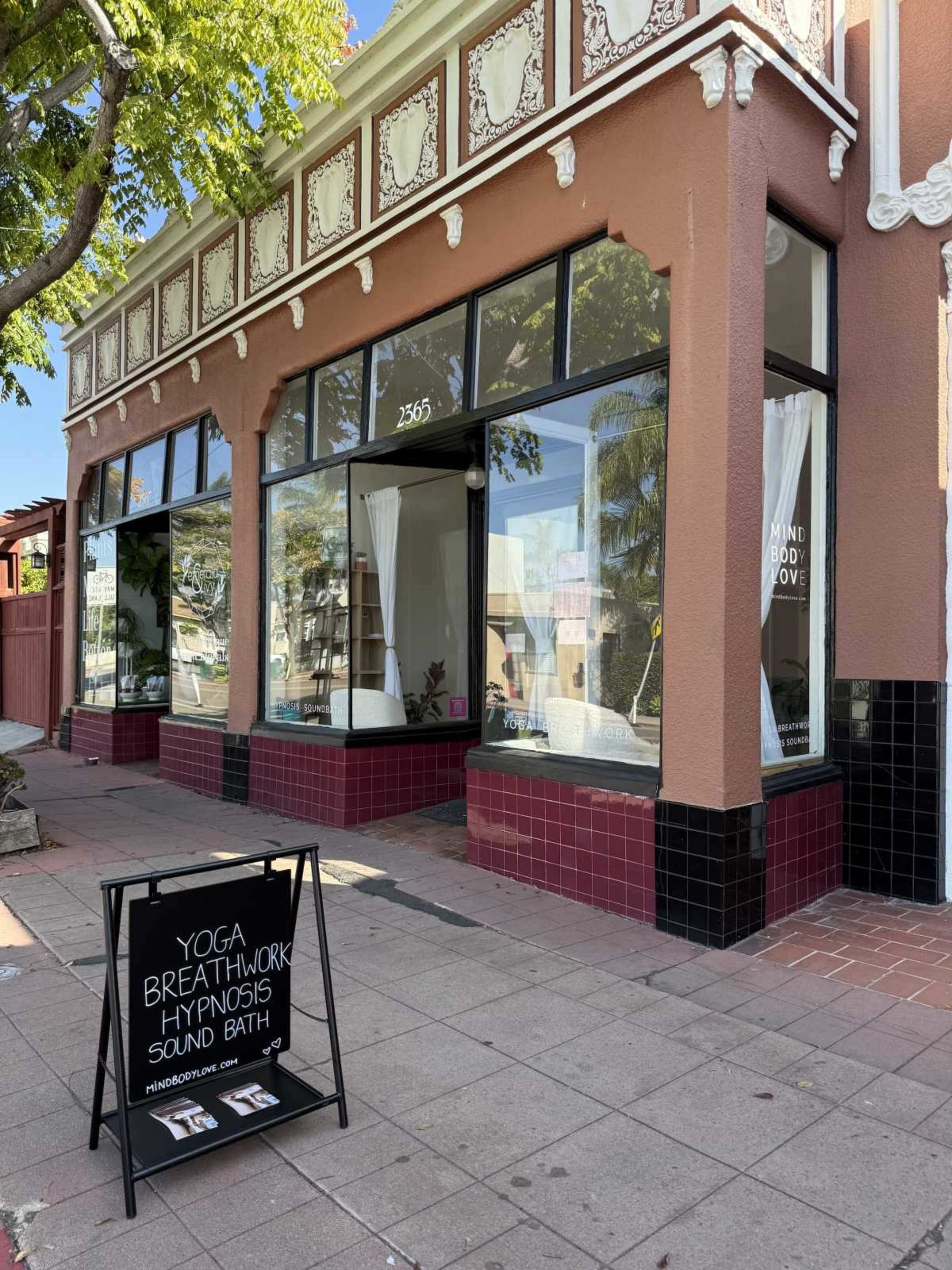 The image shows a yoga studio with large windows displaying promotional signs, located at 2565 on a street corner.