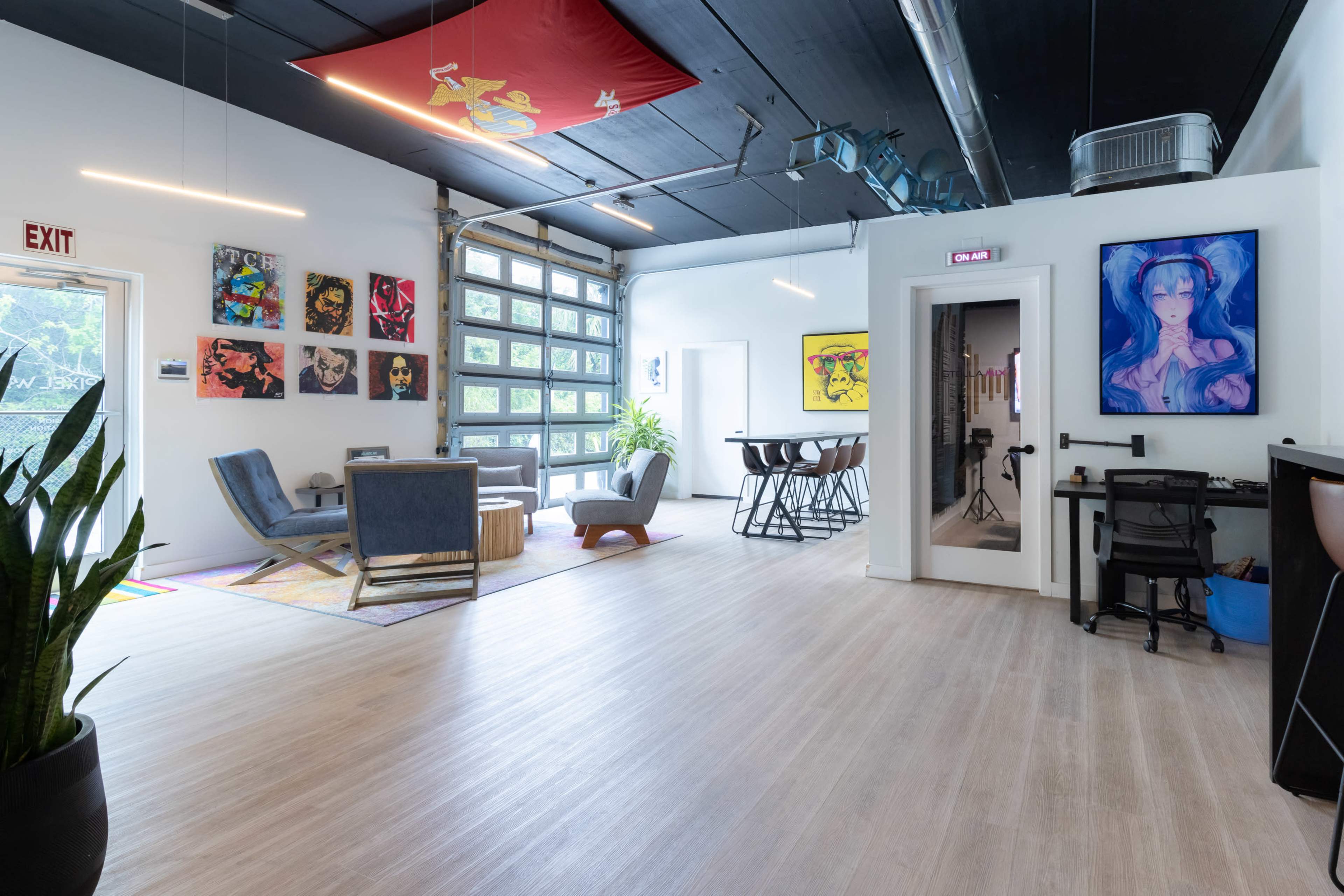 A spacious, modern interior with artwork on the walls, seating areas, and a large garage door.