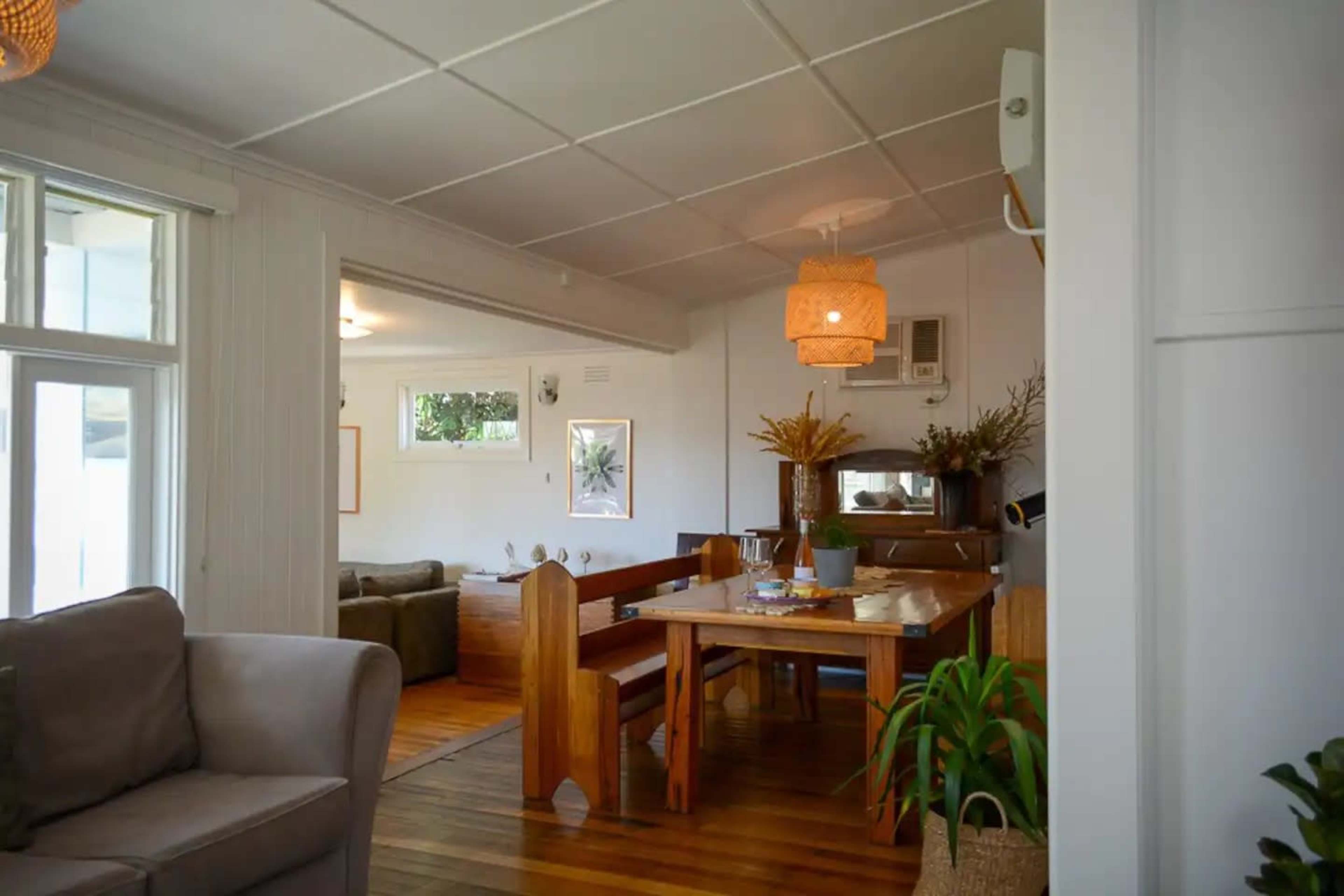A spacious interior features a dining area with a wooden table, surrounded by chairs, and leads to a cozy living room area.