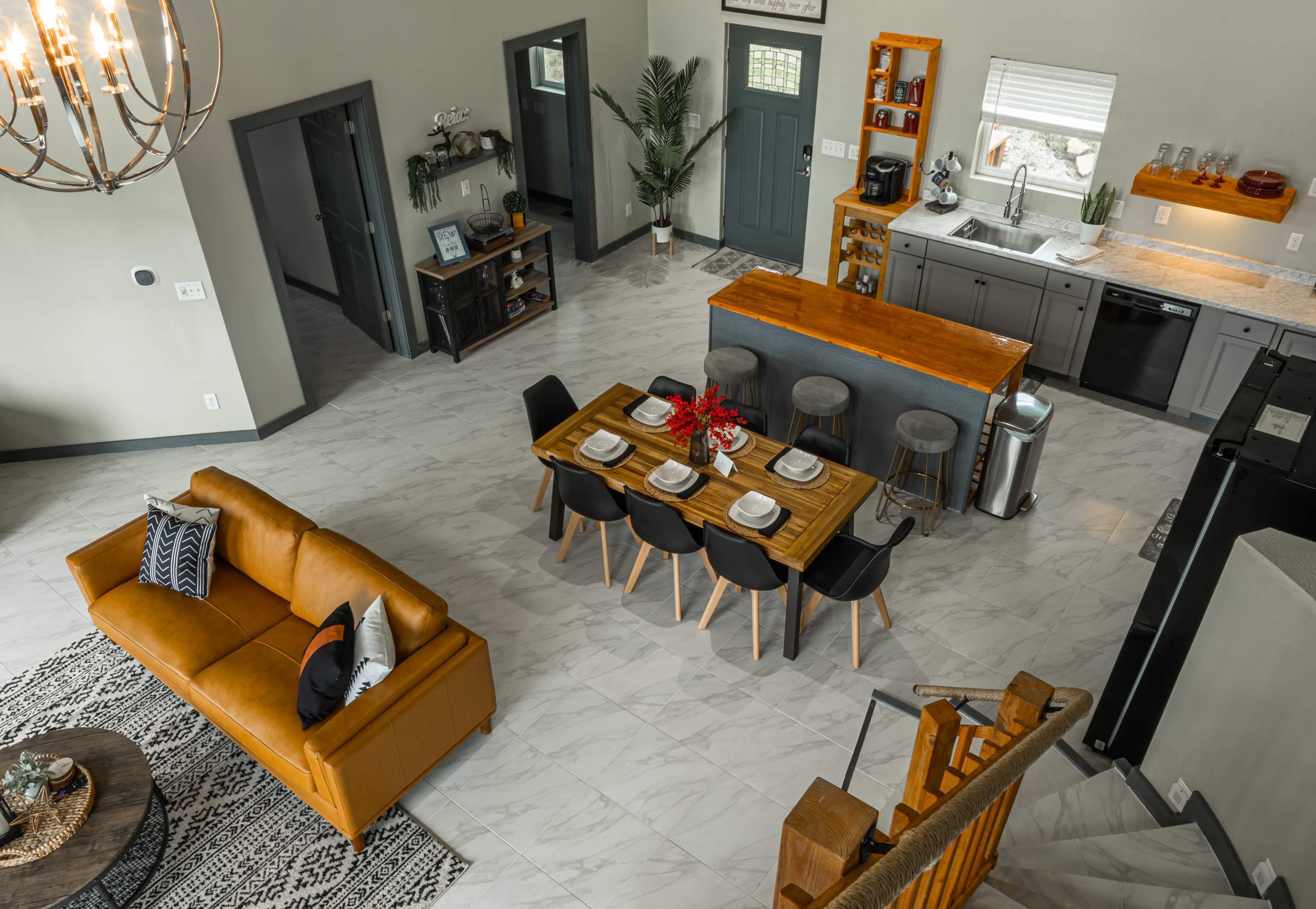 A modern kitchen and dining area with a wooden dining table set for a meal, surrounded by chairs, and a sofa positioned nearby.