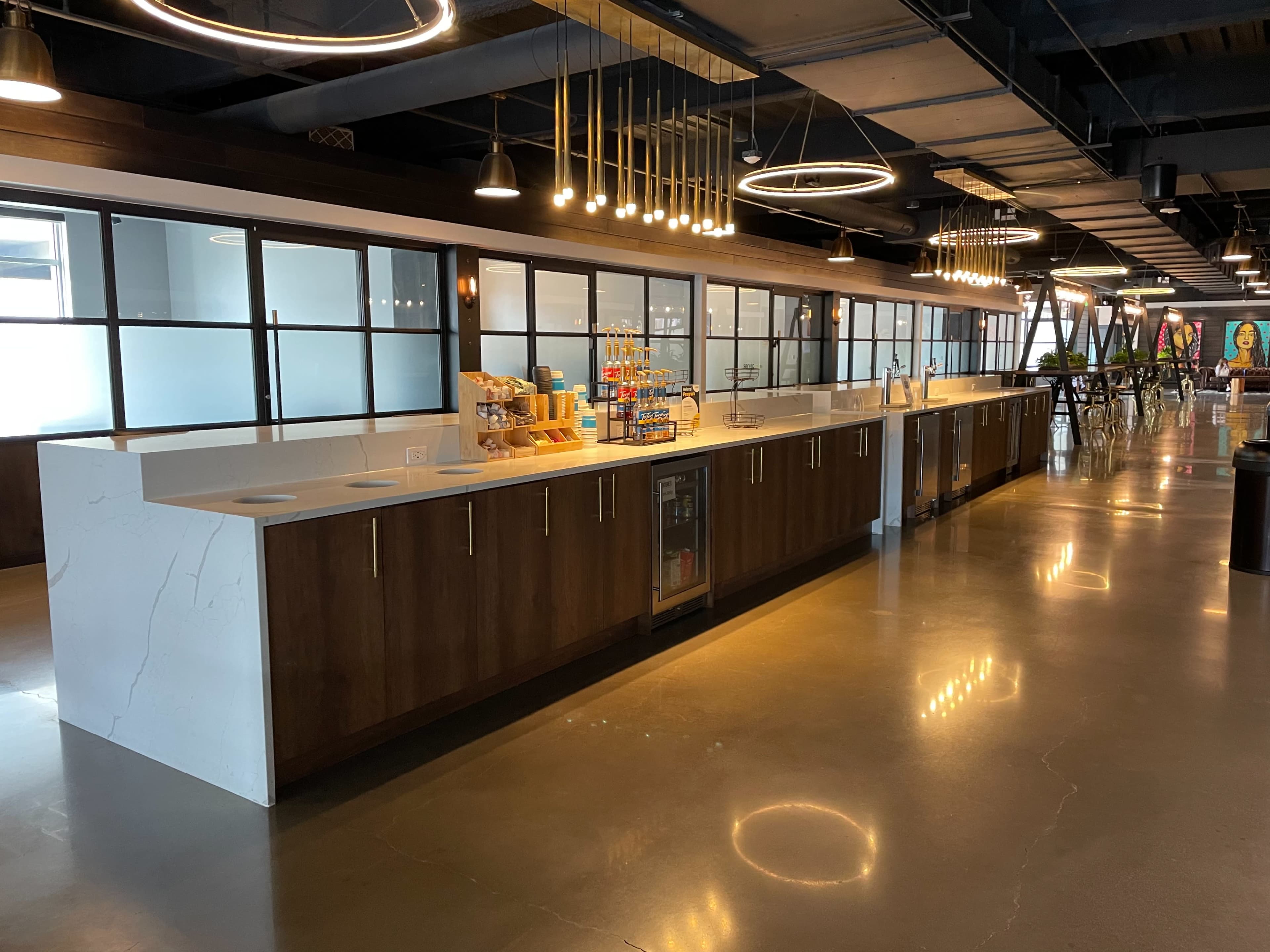 A modern kitchen area with a long countertop, open shelving, and industrial lighting fixtures overhead.