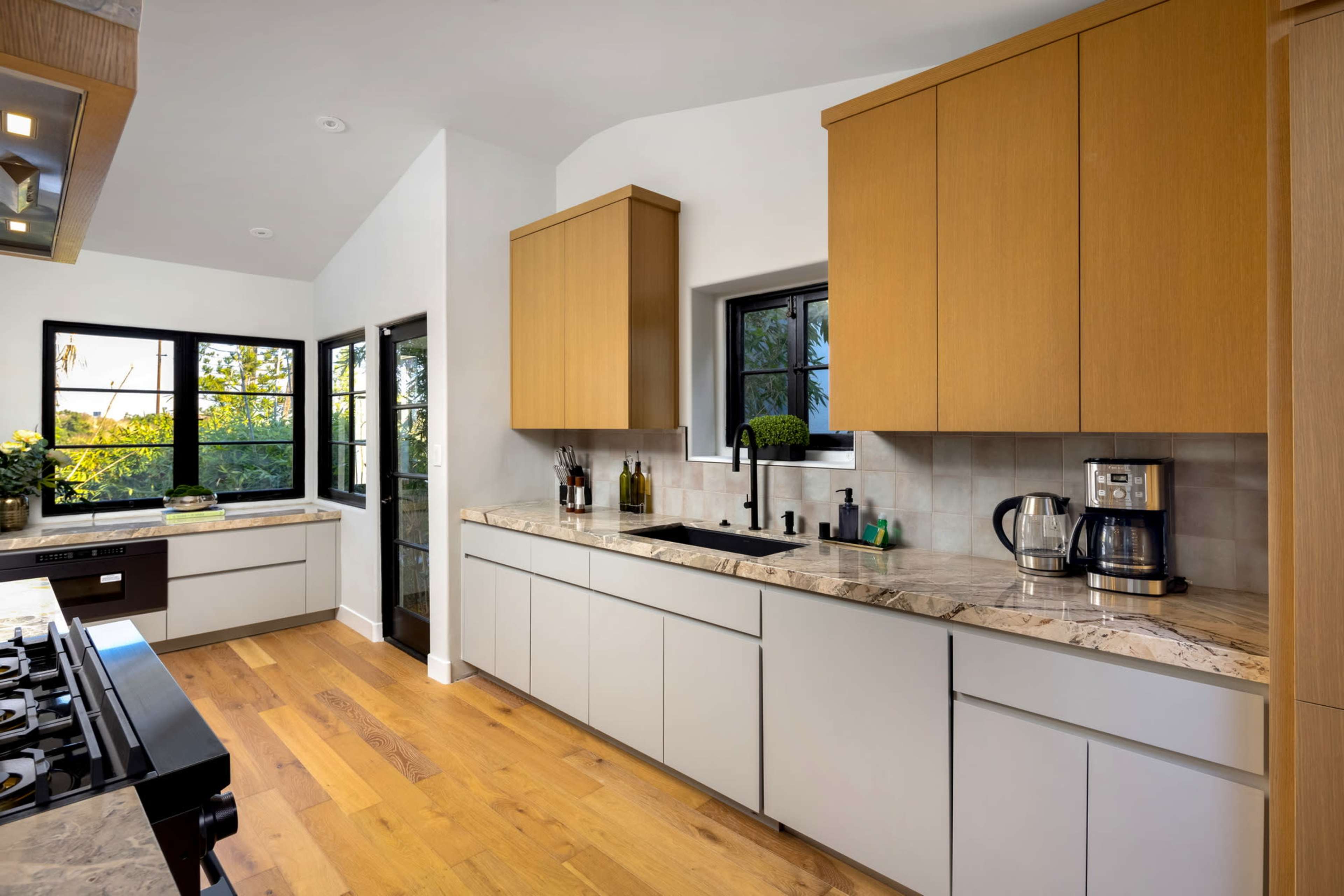 A modern kitchen features wooden cabinetry, a marble countertop, and stainless steel appliances.