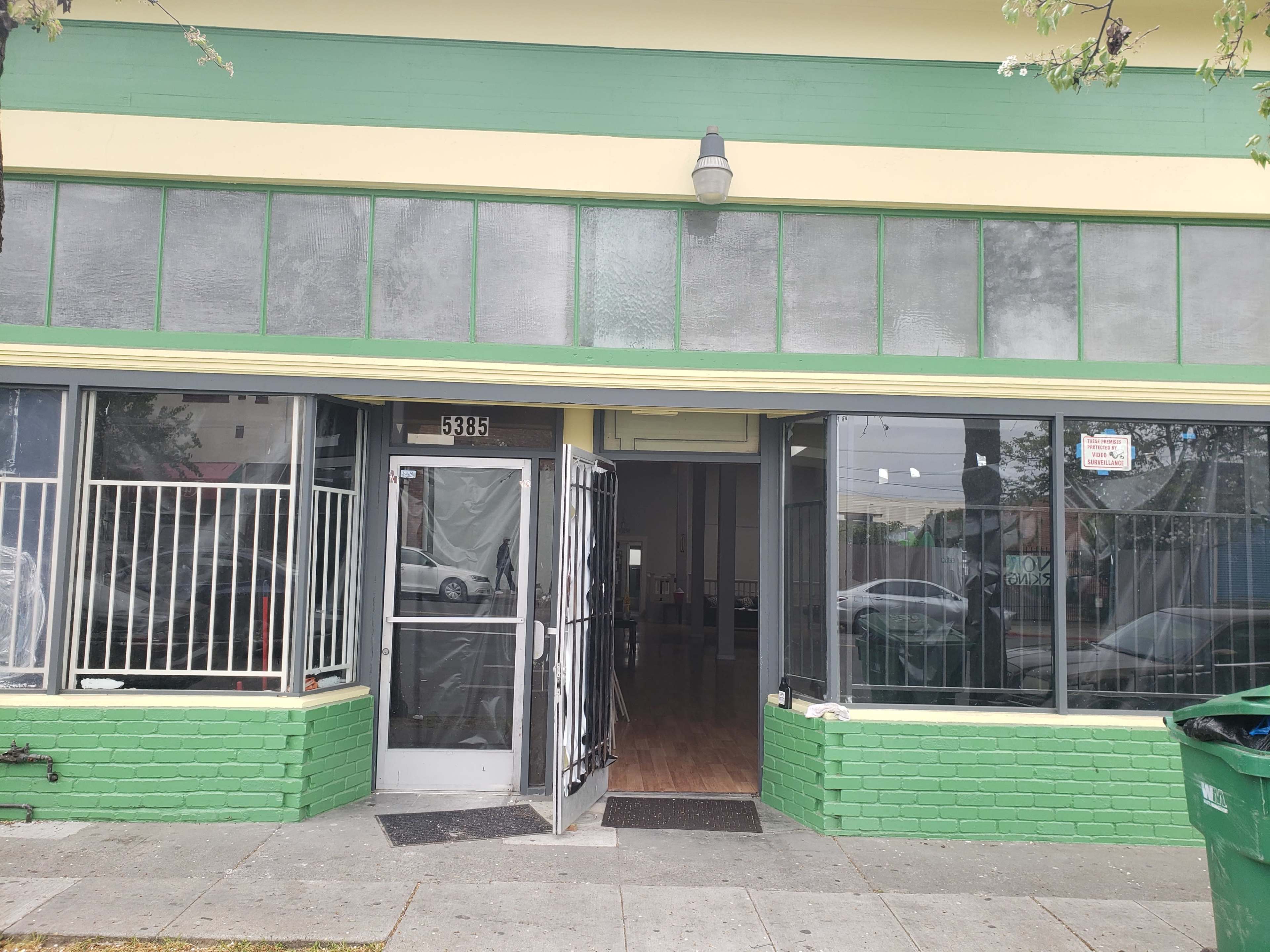 A storefront with large windows and a green-painted exterior, featuring double doors at the entrance.