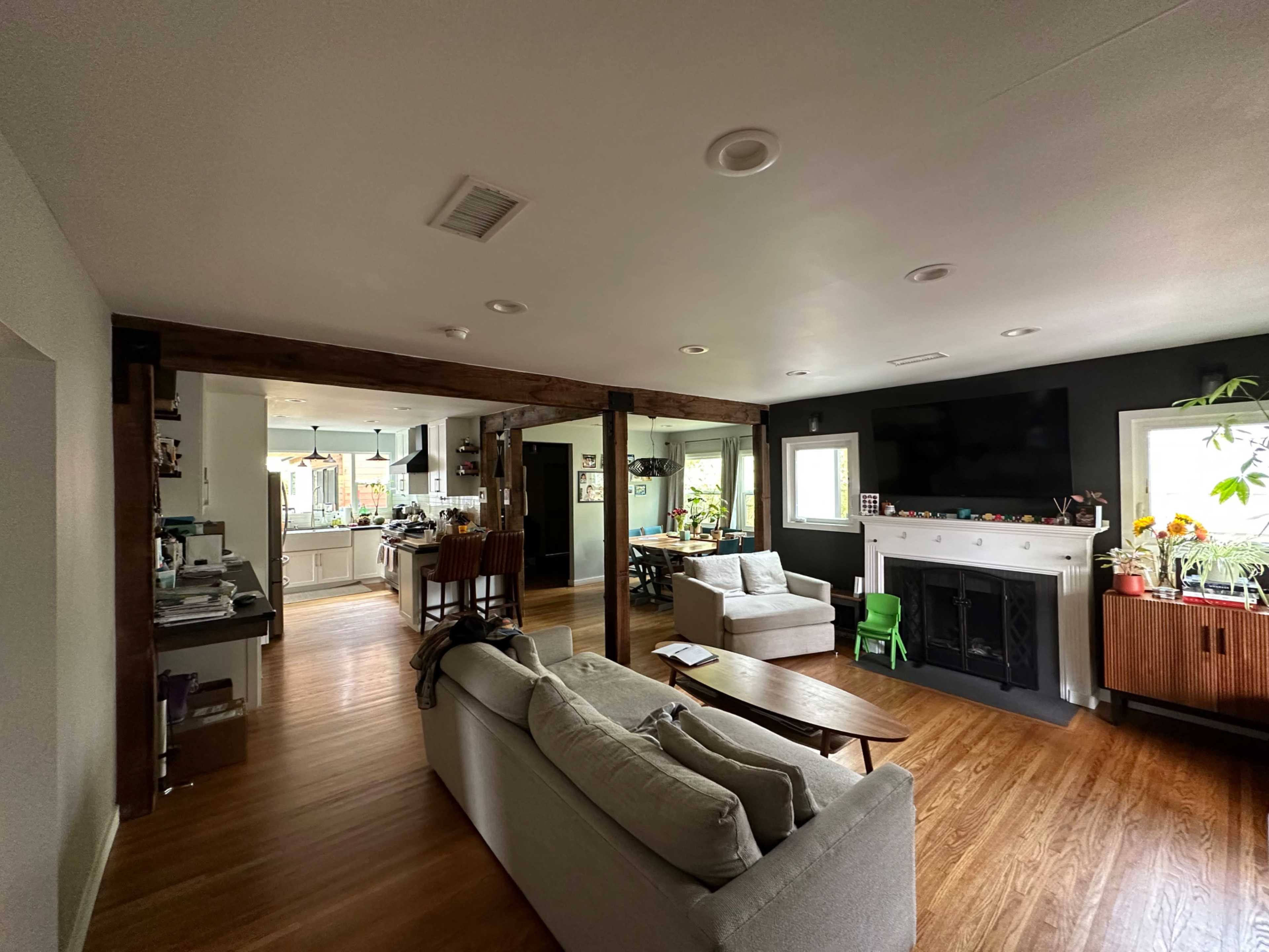 The image shows a spacious living room with a light-colored sofa and a coffee table, leading into a kitchen area visible in the background.