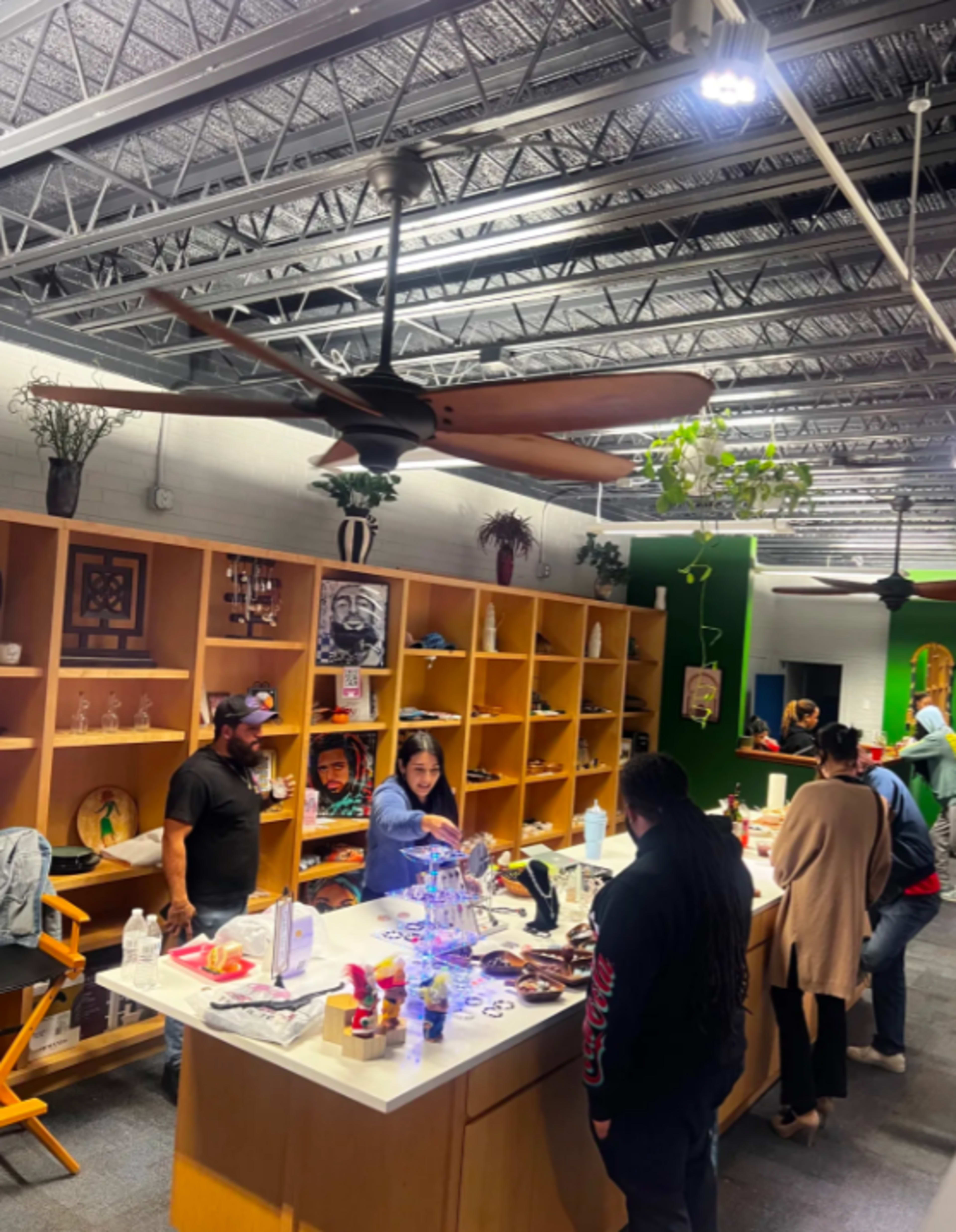 A group of people is engaging at a counter in a brightly lit store, surrounded by shelves featuring various decorative items.