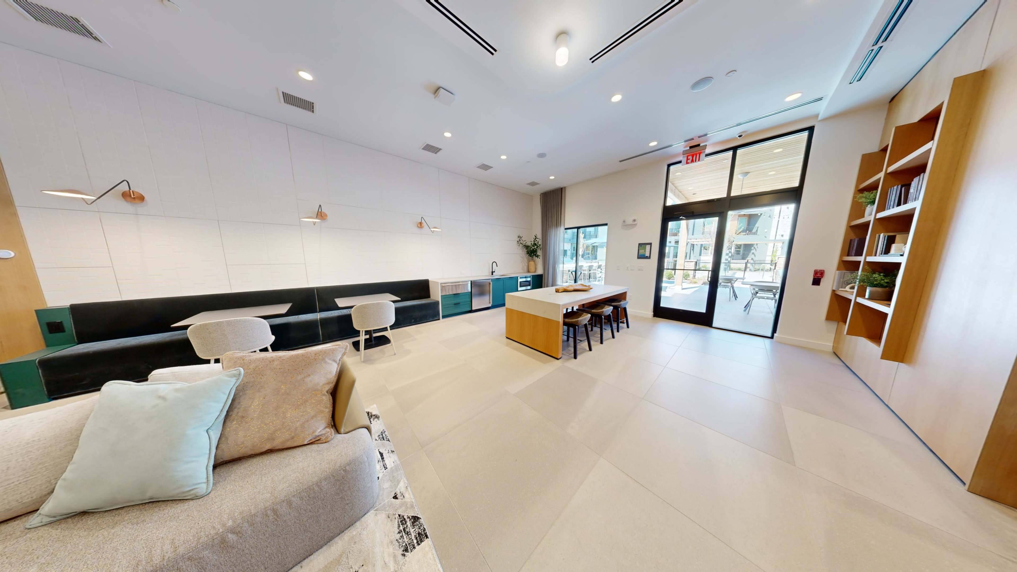 A modern lounge area with a sectional sofa, a dining table, and large windows opening to an outdoor seating area.