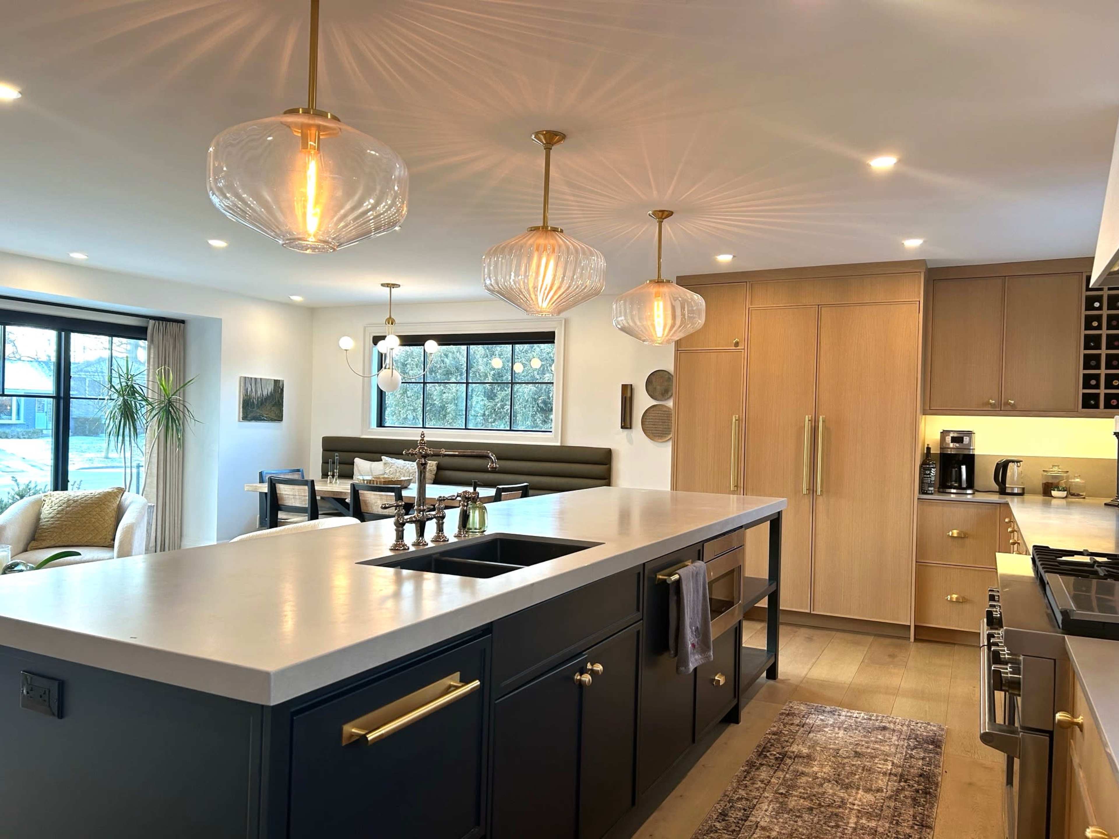 The image shows a modern kitchen with a large island, pendant lights, and cabinets in neutral tones.