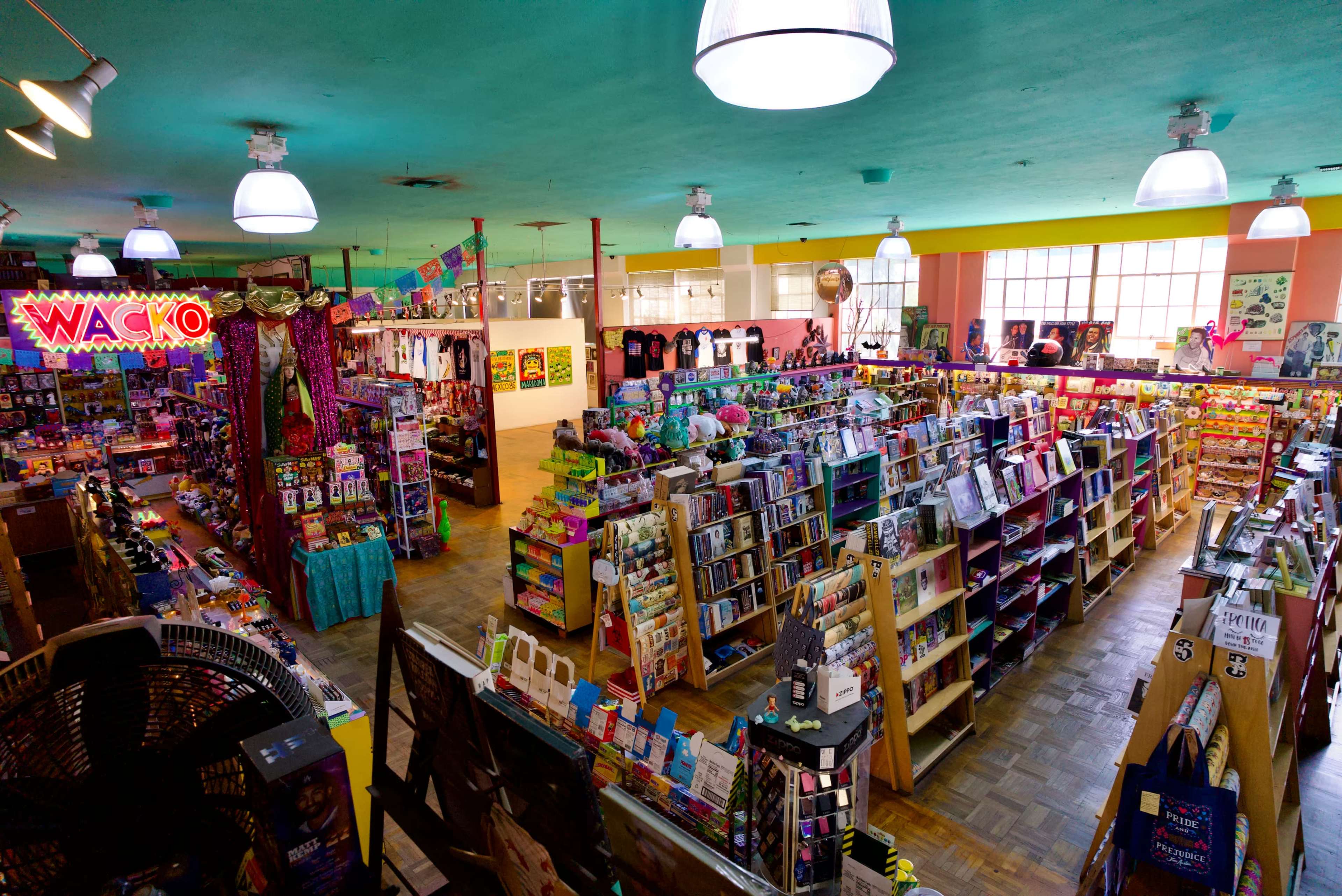 The image shows an expansive and colorful gift shop filled with shelves of books, toys, and various novelty items under bright lighting.