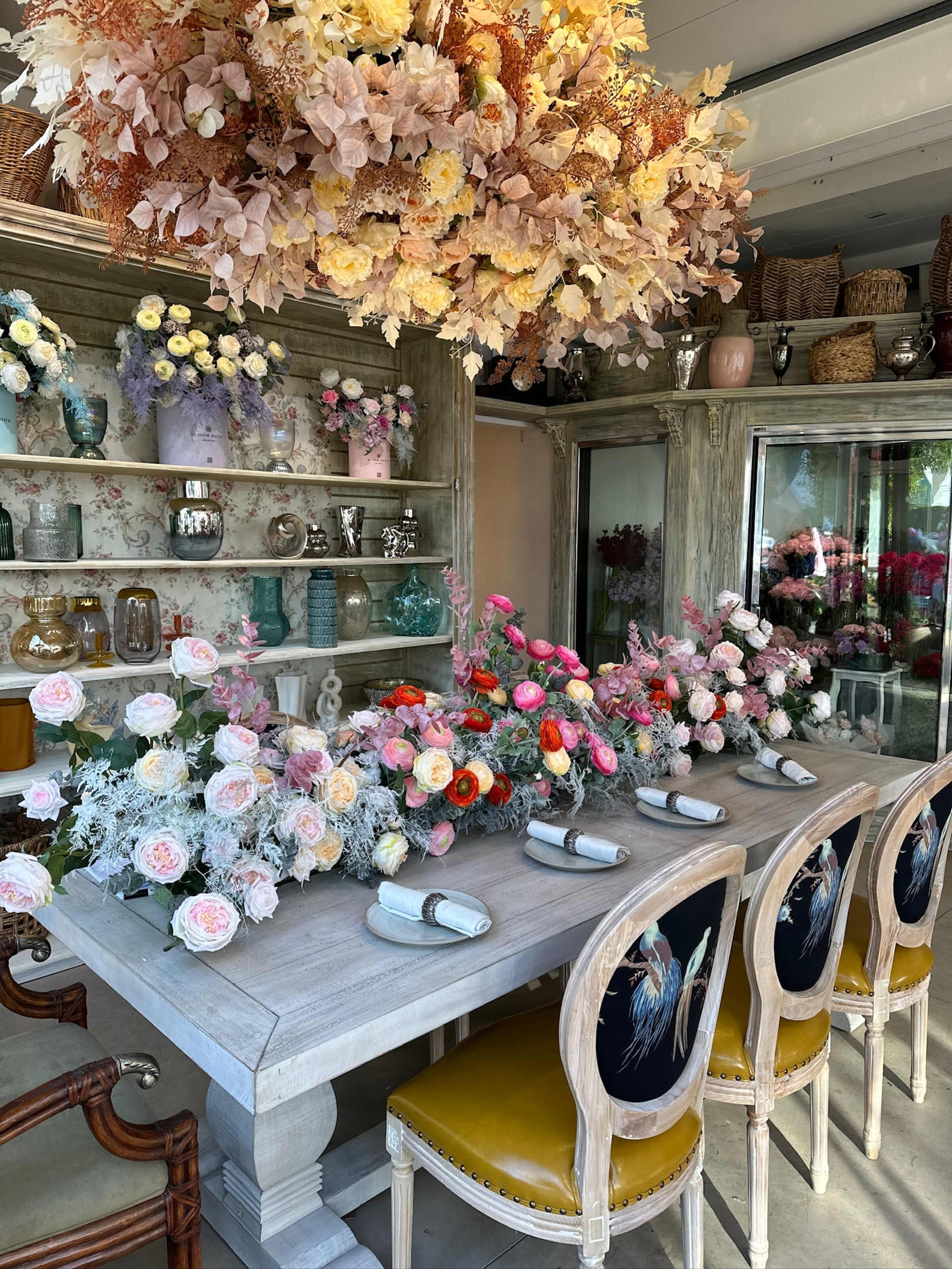 A dining area features a large wooden table adorned with floral arrangements and surrounded by elegantly designed chairs.
