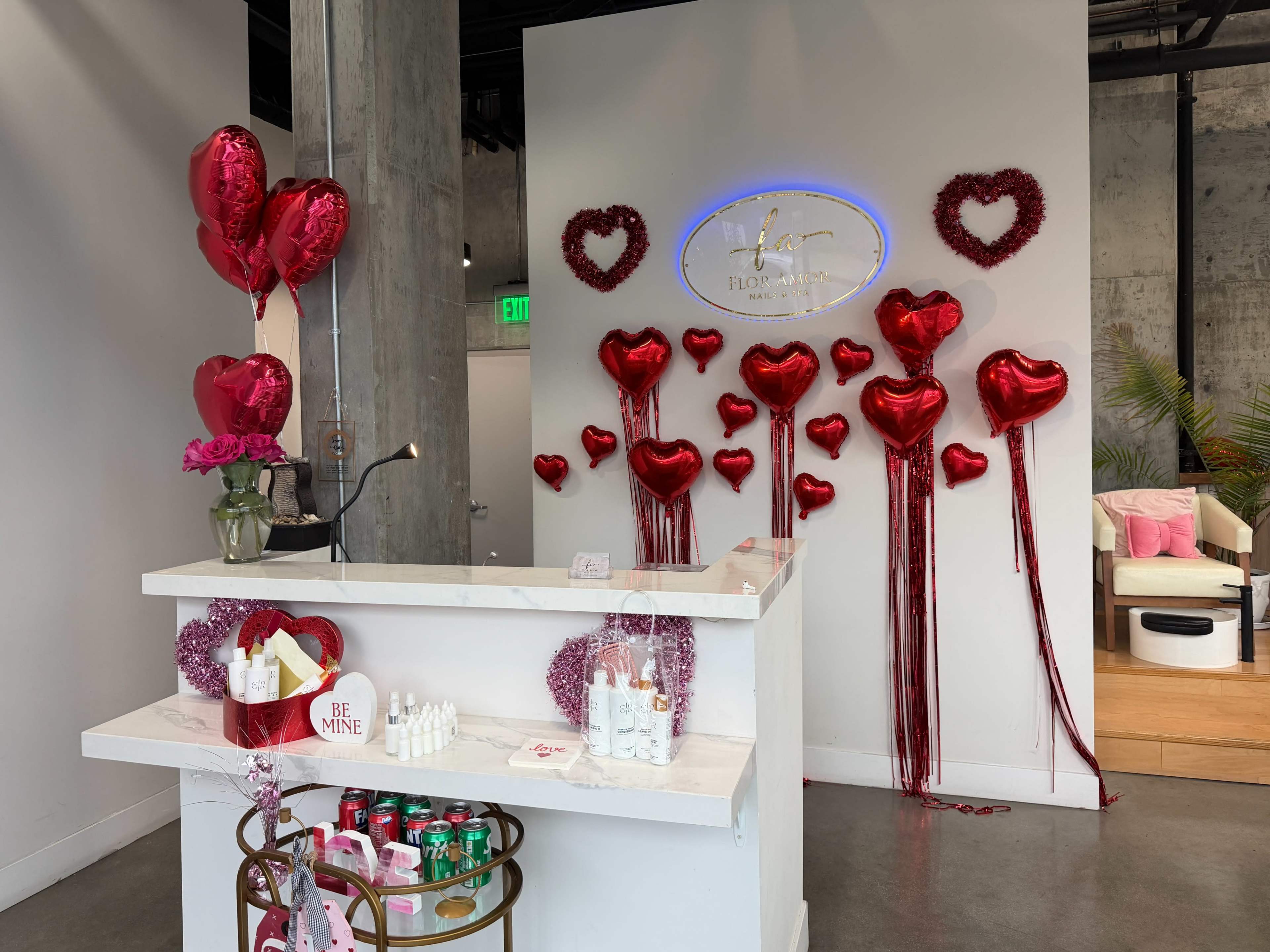 The image shows a modern reception area decorated with red heart-shaped balloons and a flower arrangement on the counter.