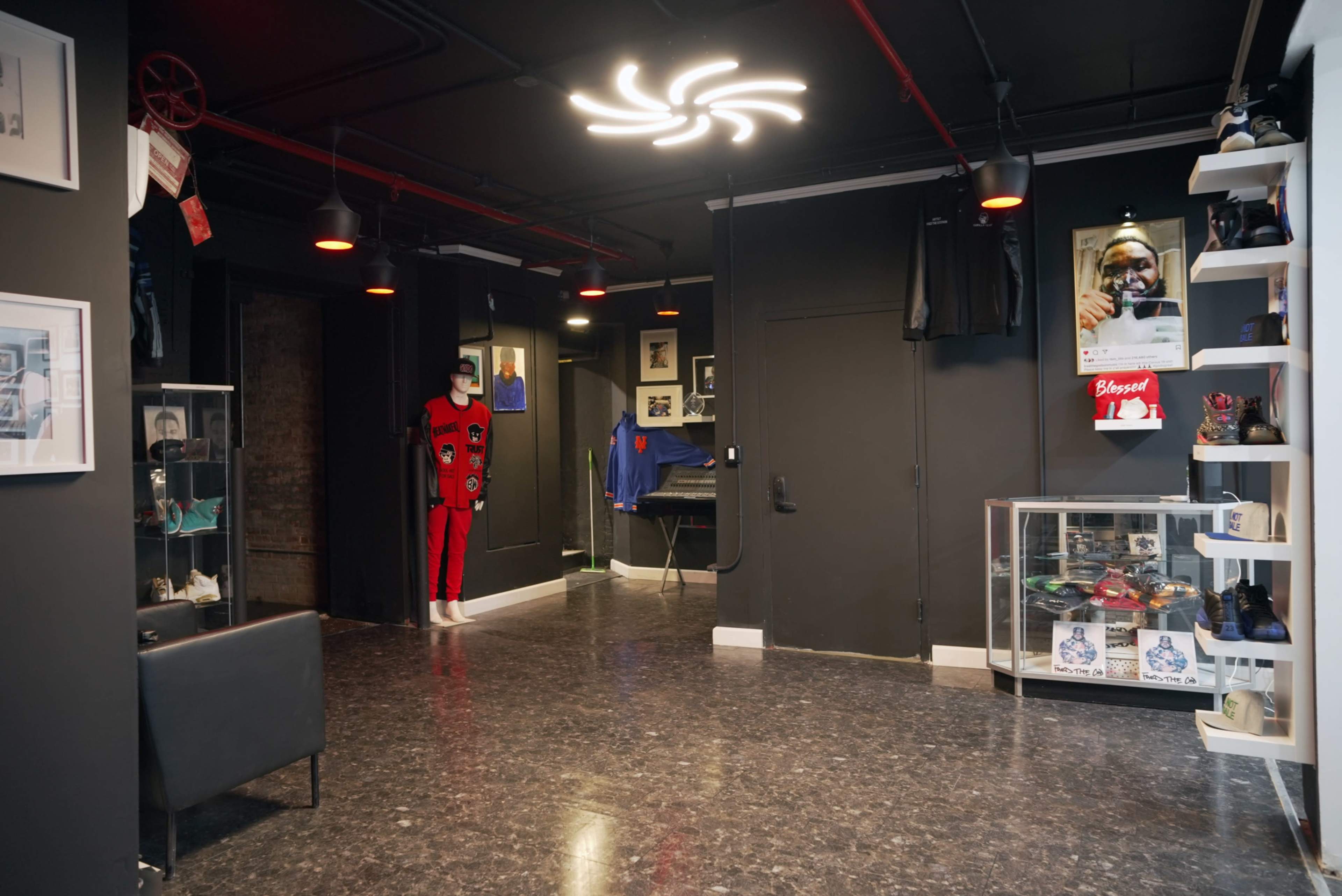 The interior of a boutique features black walls, polished floors, and displays of clothing and memorabilia.