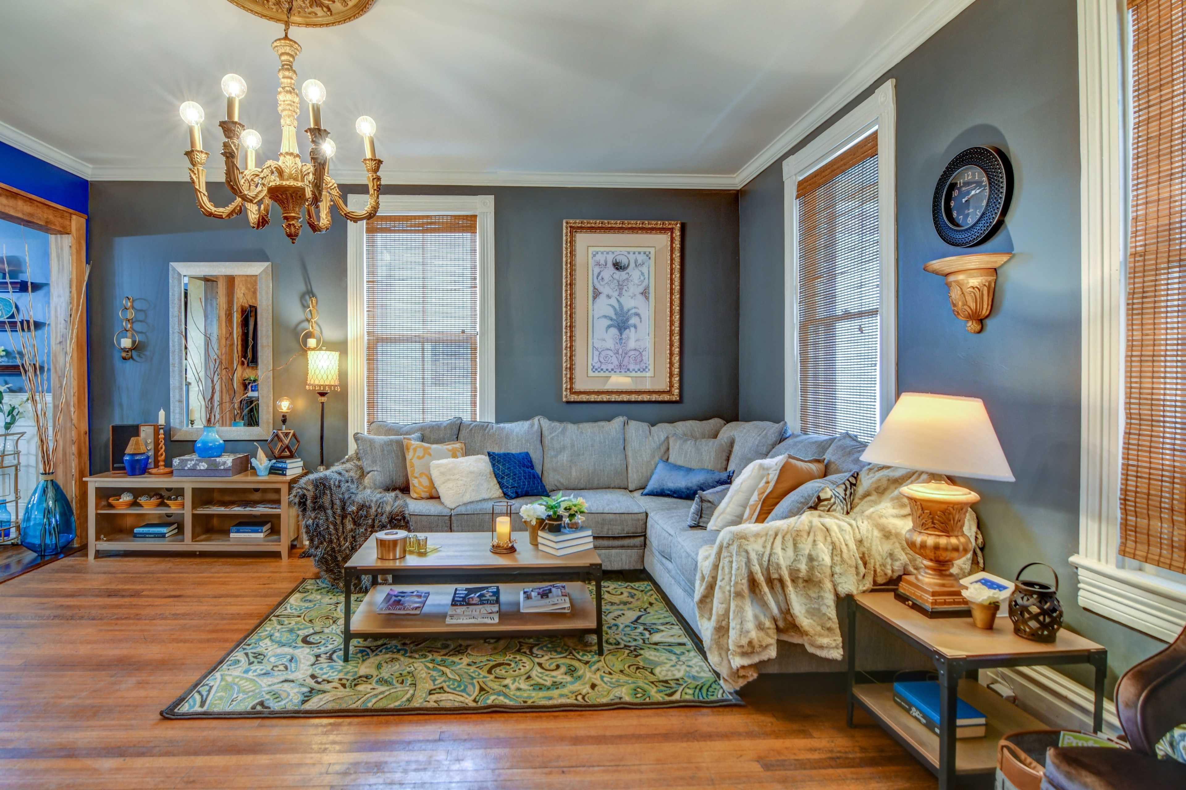 A cozy living room featuring a gray sectional sofa, wooden accents, and a decorative chandelier hanging from the ceiling.