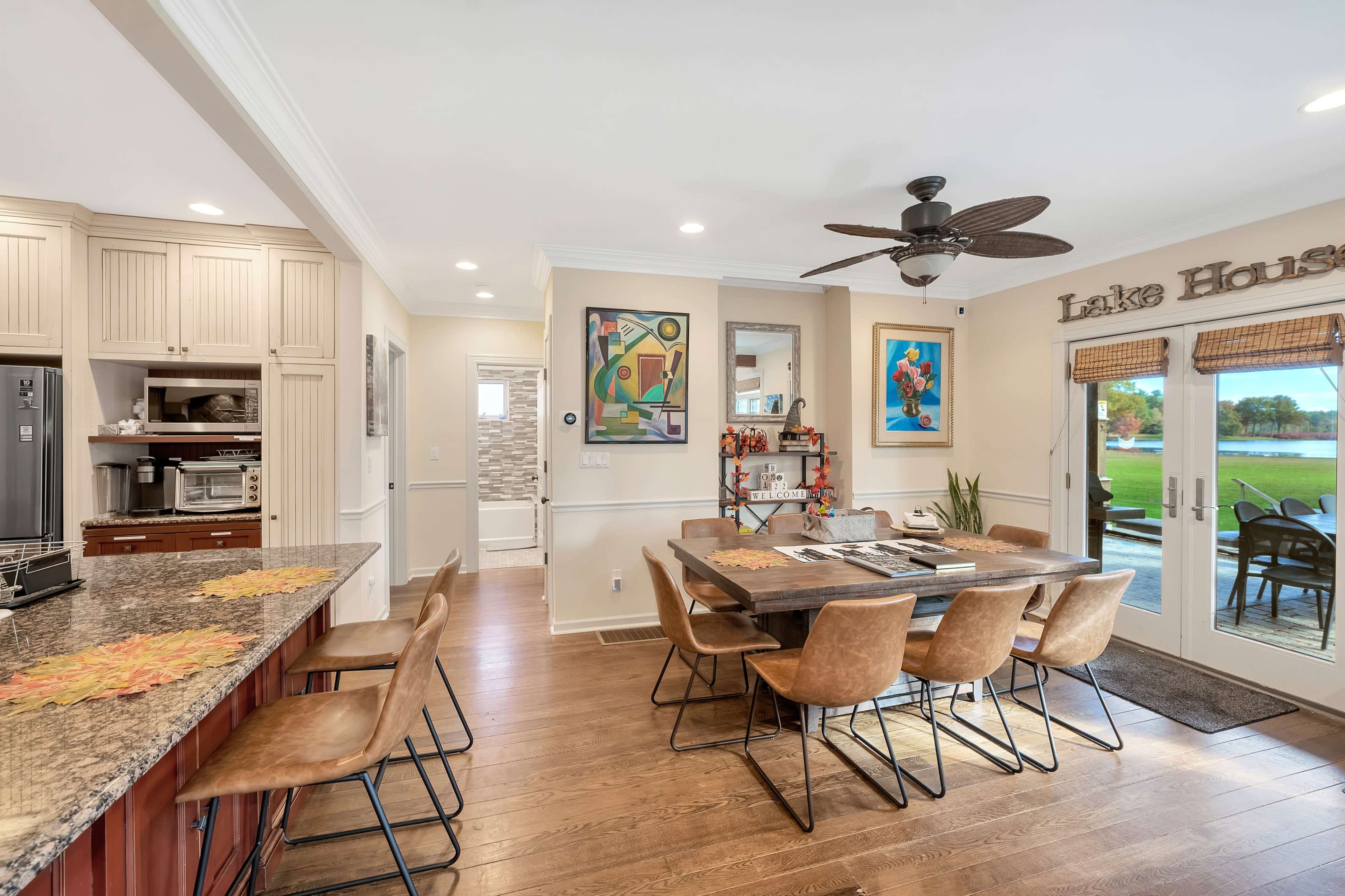 A spacious kitchen and dining area featuring a large wooden table surrounded by leather chairs, a granite countertop, and a view of a patio door leading to an outdoor space.