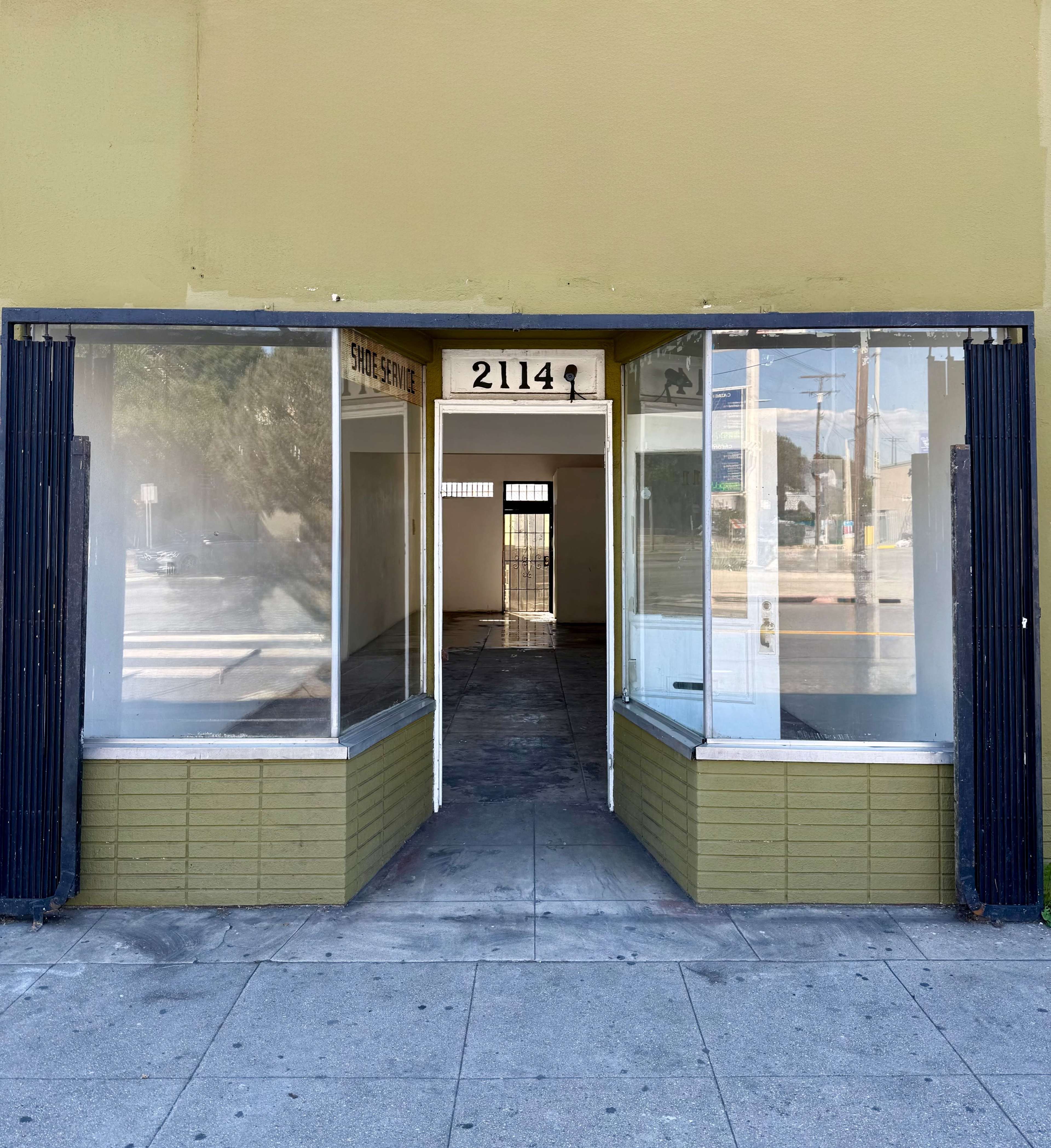 The image shows a vacant storefront with large windows on either side and a clear view into the empty interior.
