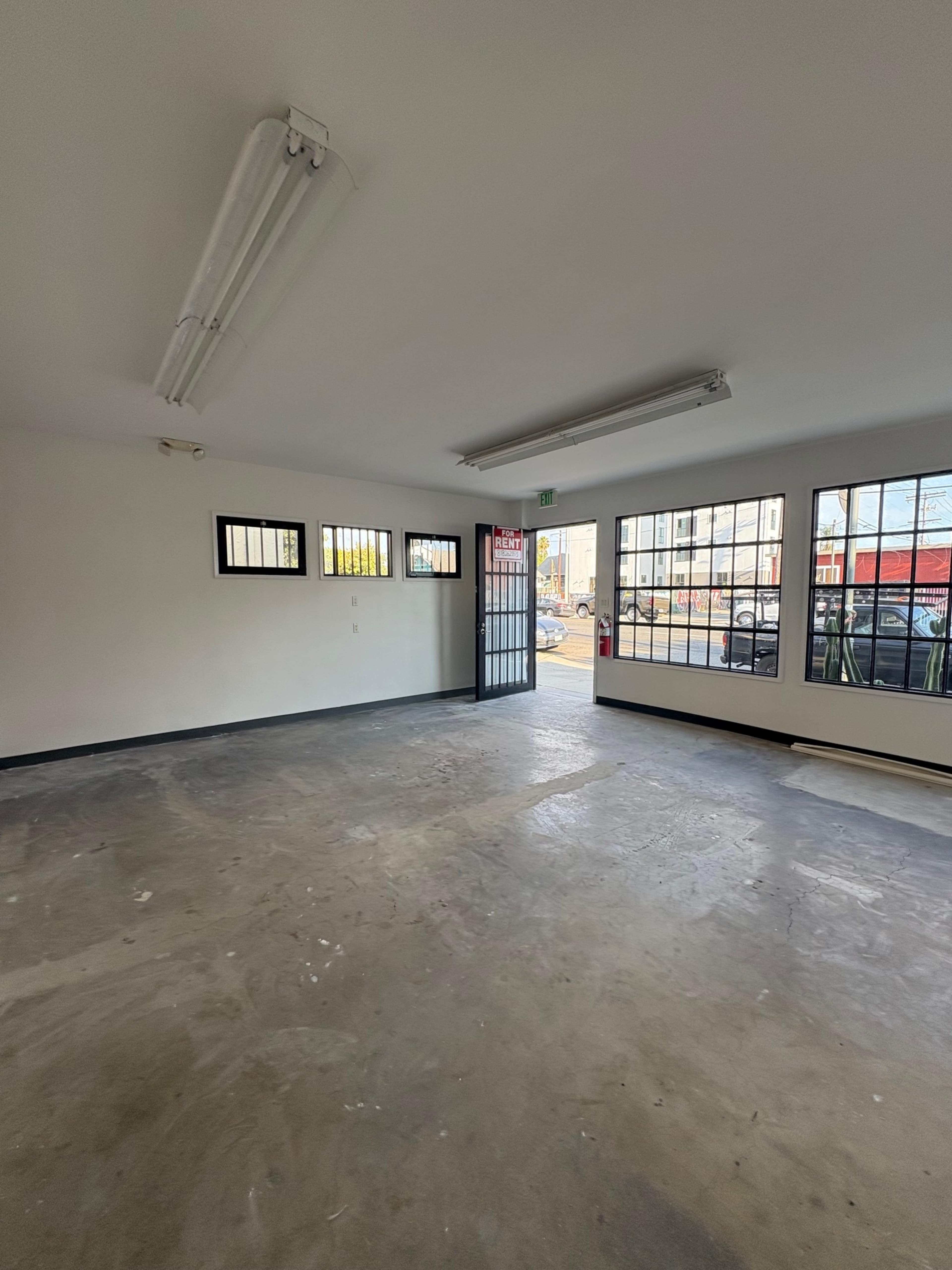 Empty modern storefront commercial space with concrete floors, large custom steel windows and oversized door. Image in South Los Angeles, Los Angeles, CA