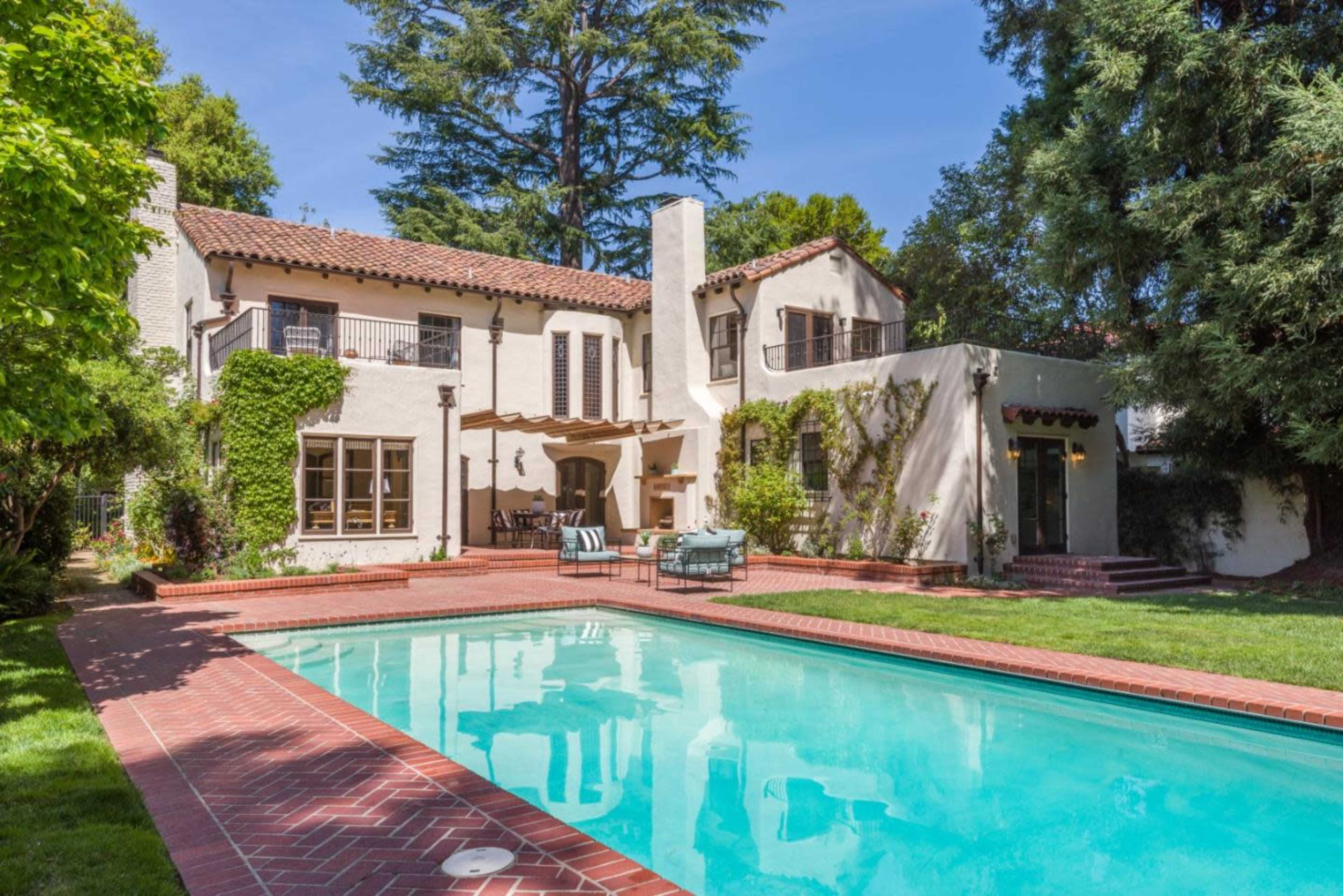 A two-story, Mediterranean-style house with a swimming pool and landscaped grounds.