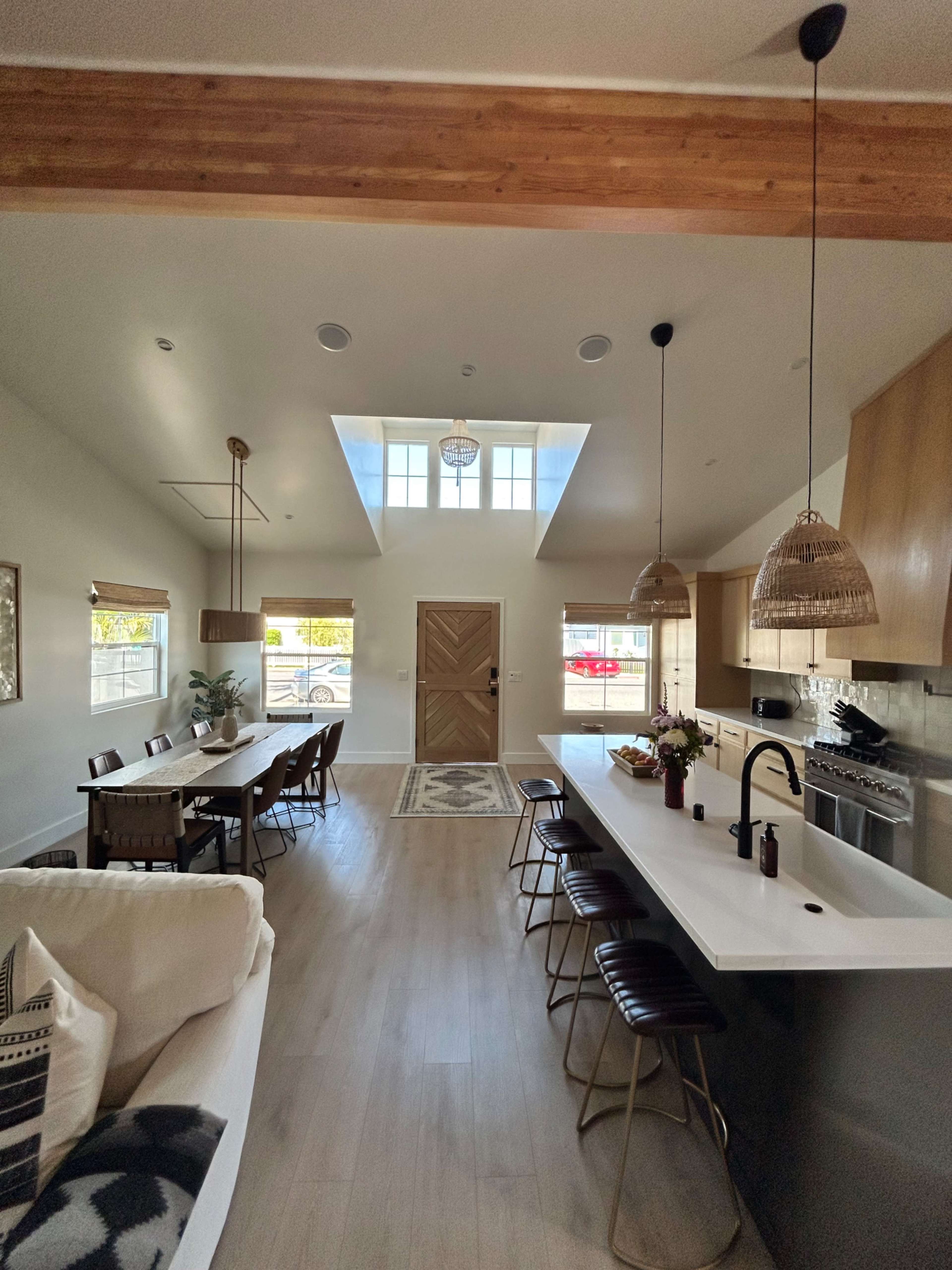 A modern open-concept kitchen and dining area with a large window and wooden beams.