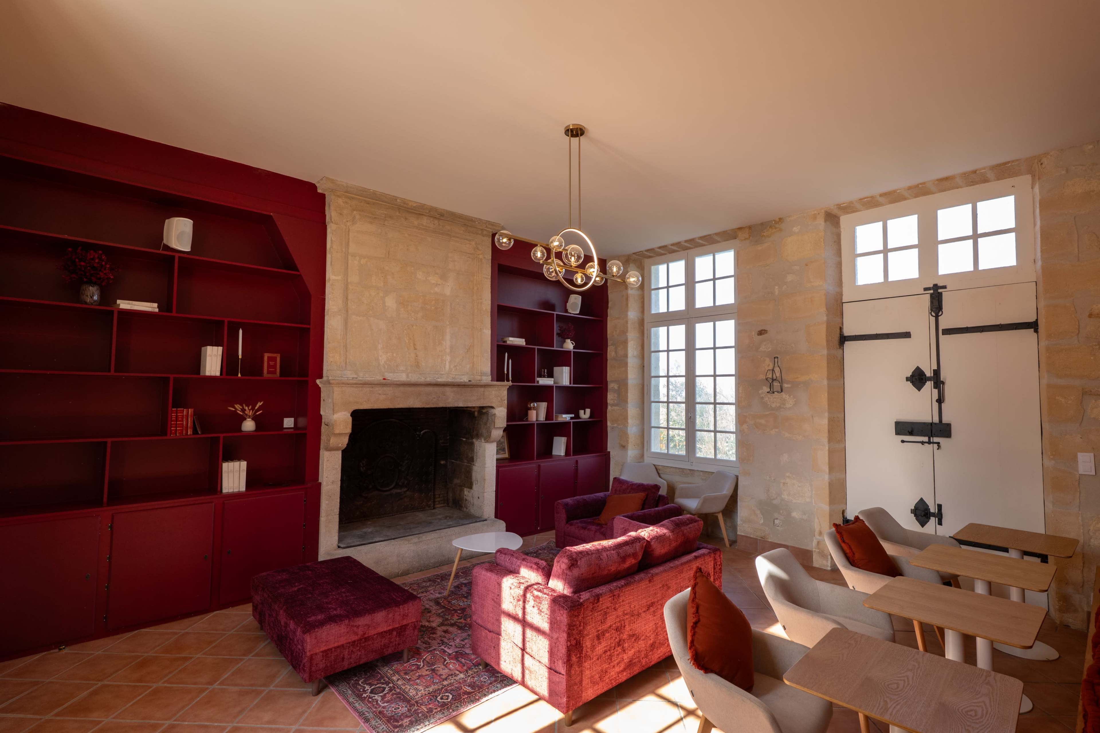 The image shows a cozy living area with red bookshelves, a fireplace, and a mix of modern and traditional furniture.
