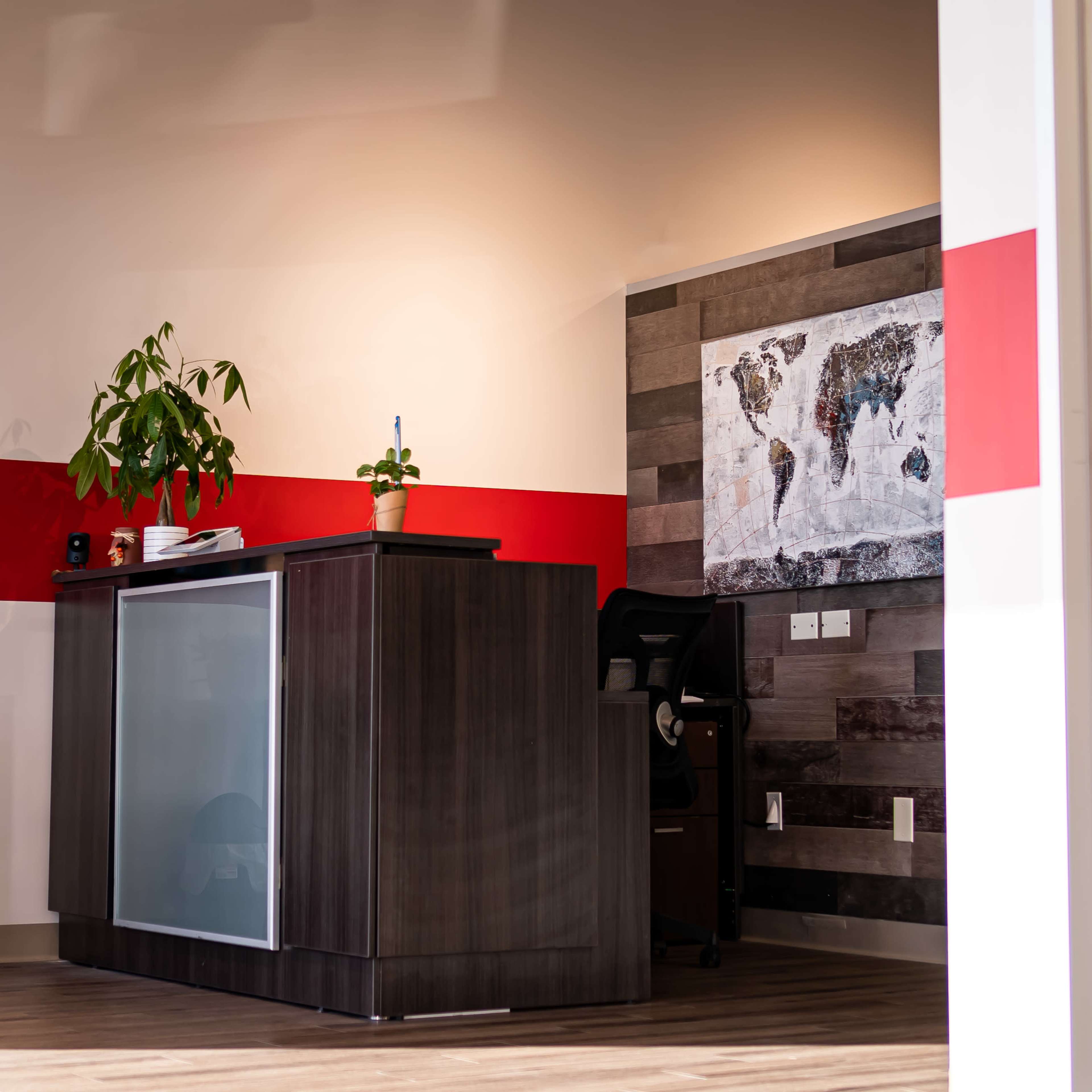 A modern office reception area featuring a desk, a potted plant, and a world map on the wall.