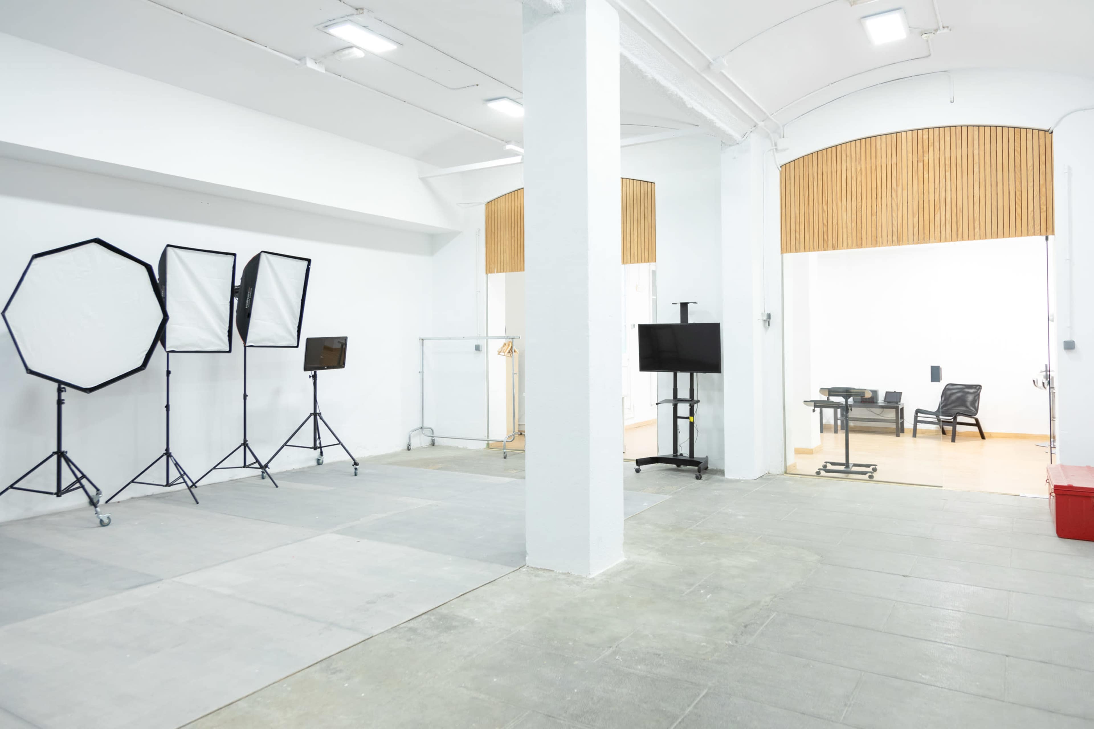 A spacious studio with photography equipment on one side and an area with a desk and chairs on the other.