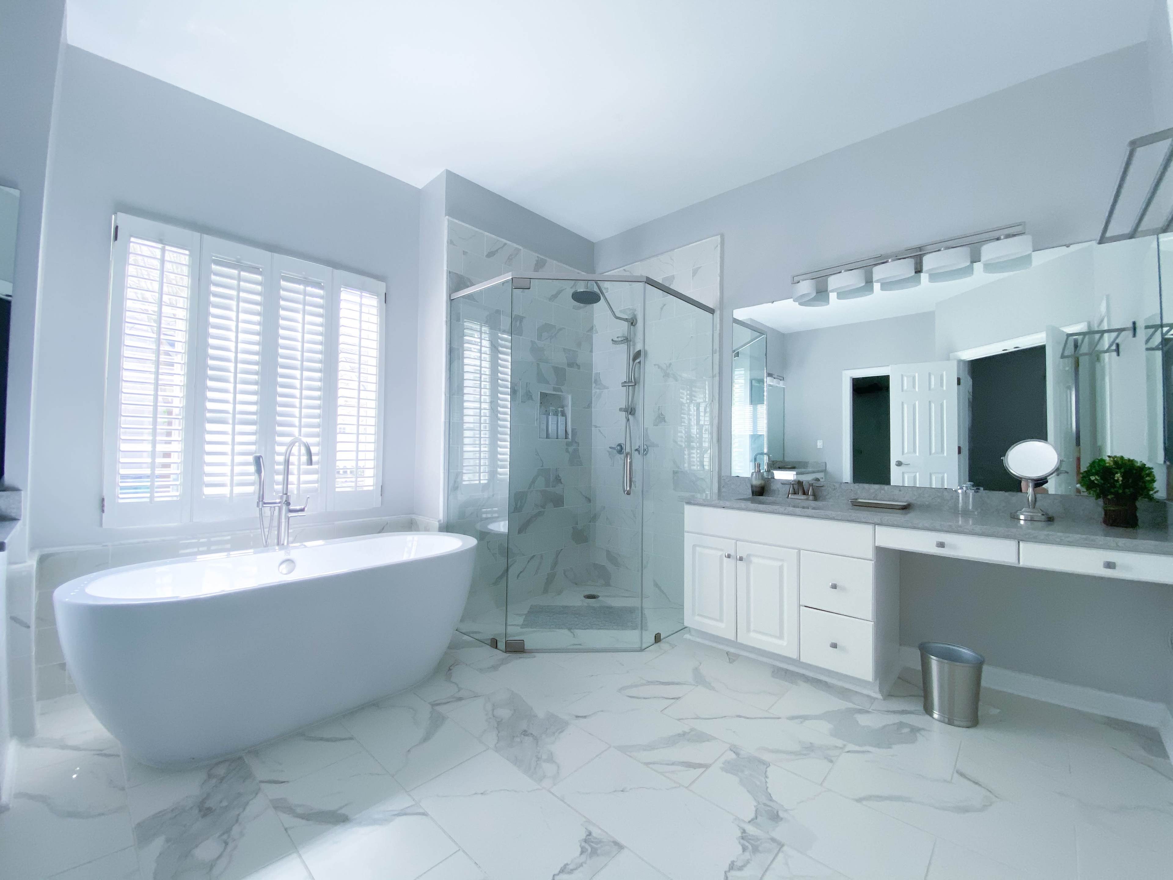 A modern bathroom featuring a freestanding bathtub, a glass-enclosed shower, and dual sinks with a large mirror.