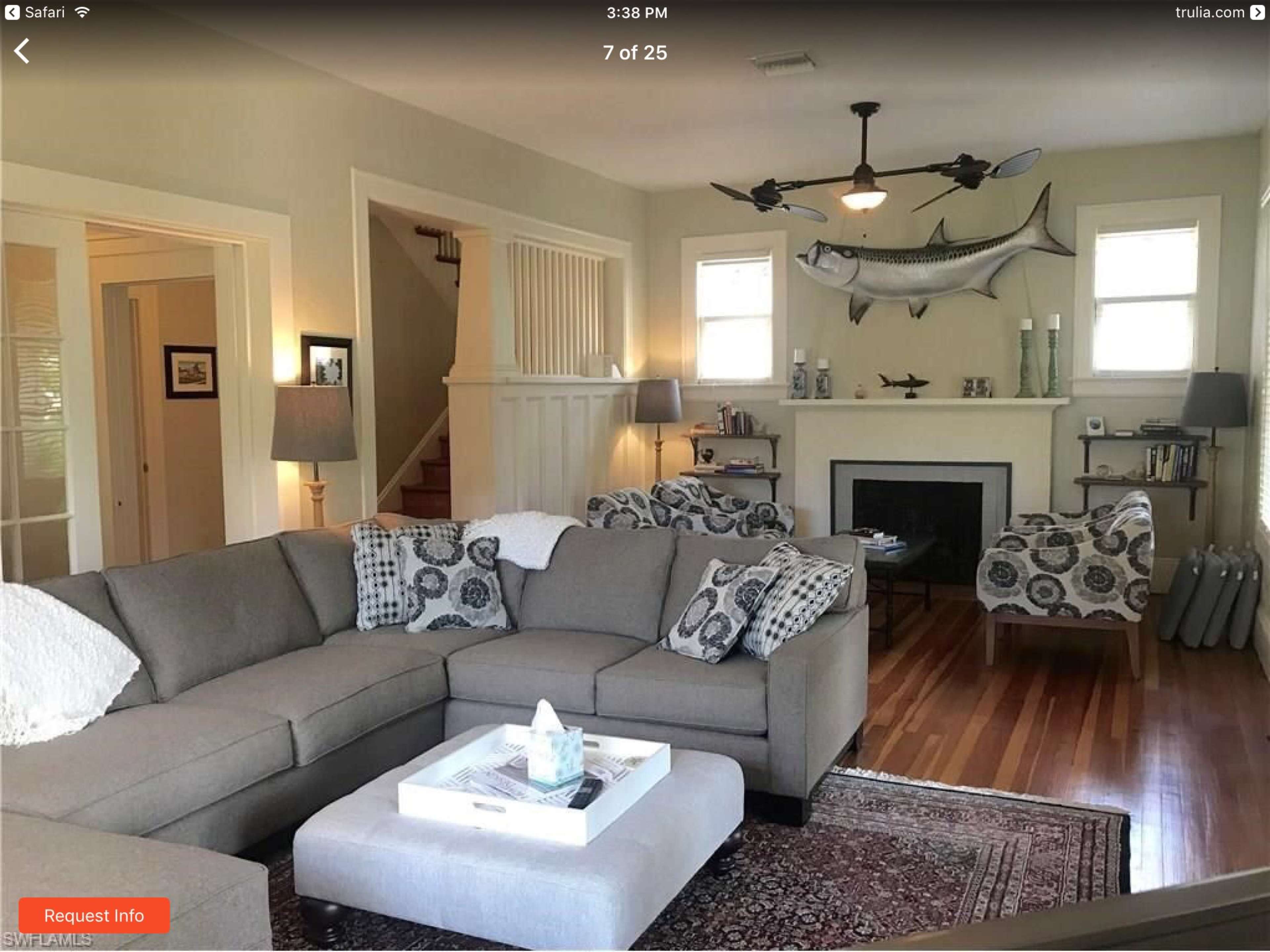 The living room features a gray sectional sofa, two patterned chairs, and a fireplace with a mounted fish decoration on the wall.