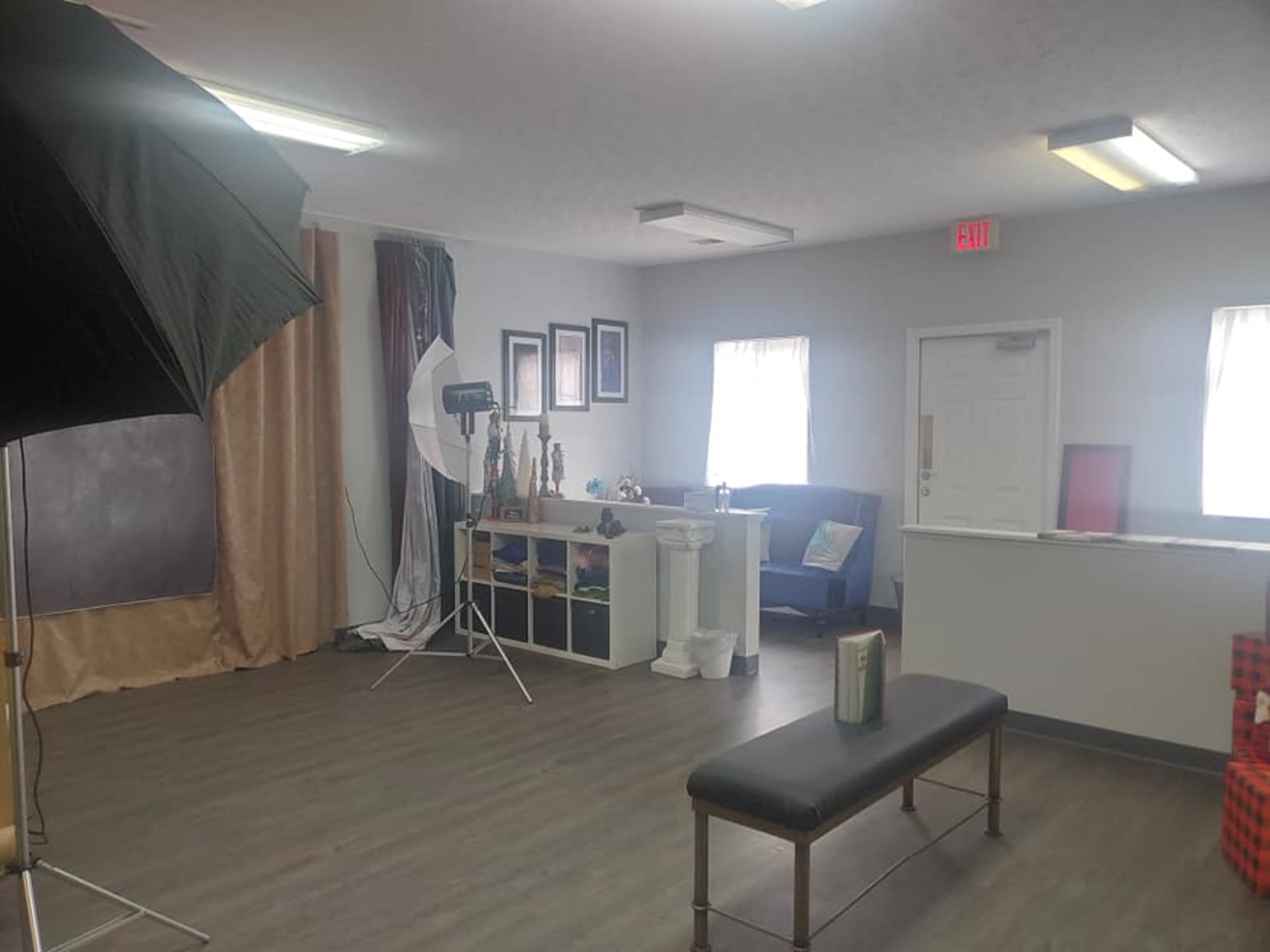 A photography studio with a backdrop, lighting equipment, a bench, and various props arranged on a shelf.