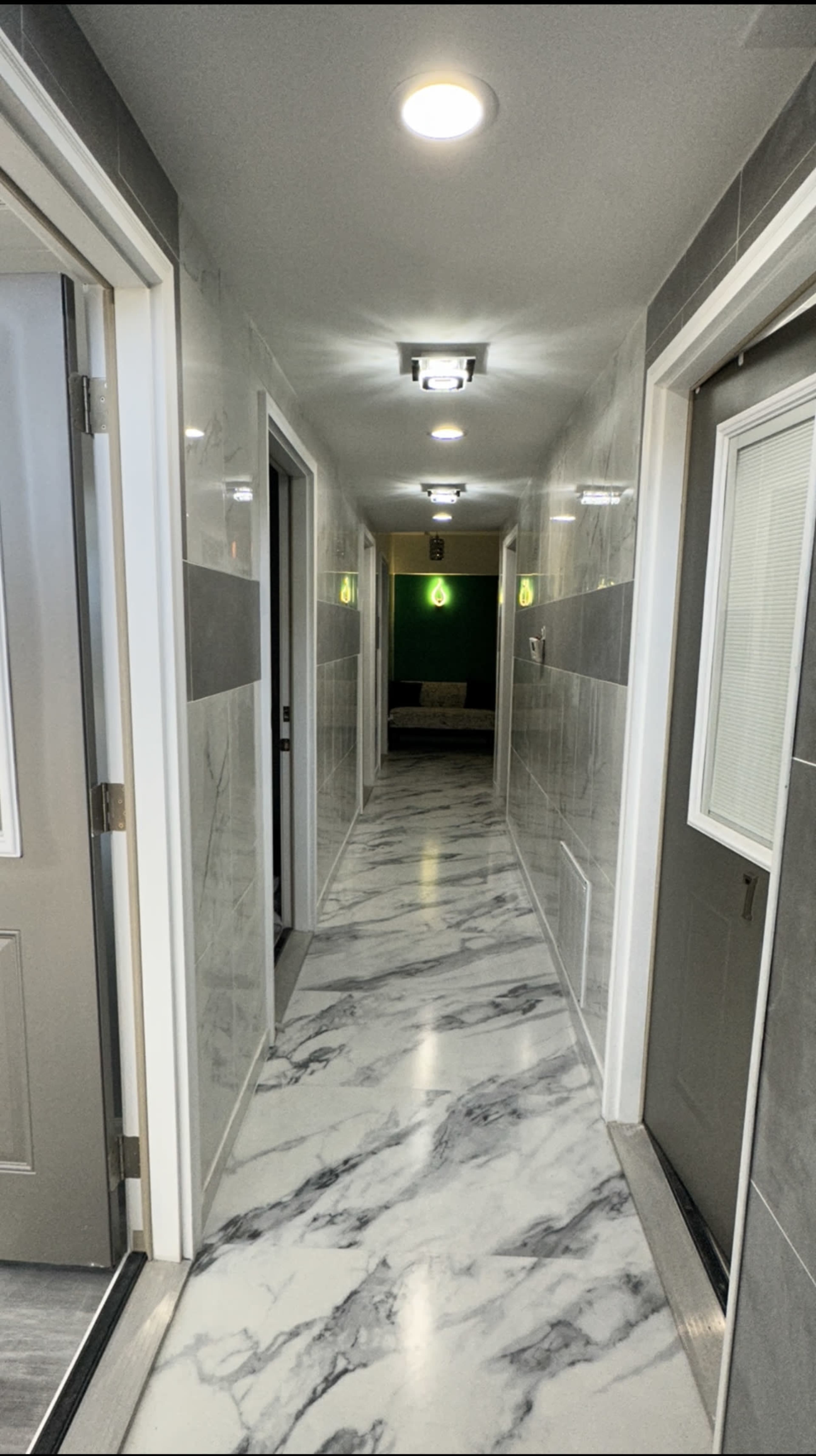 A marble-floored hallway with doors on either side and illuminated ceiling lights.